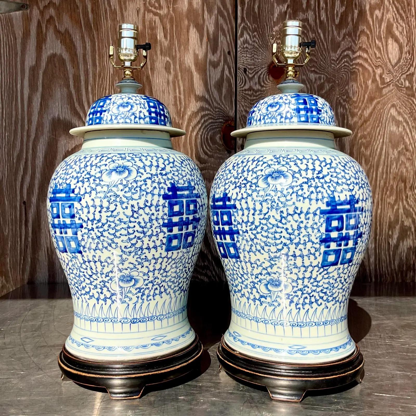 A vintage pair of Asian ceramic lamps. The iconic blue and white design with large Asian characters. Pest of wooden plinths. Acquired from a Palm Beach estate.