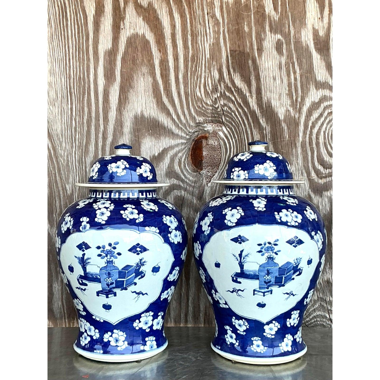 Infusez une élégance intemporelle dans votre espace en utilisant cette paire de pots à gingembre vintage asiatique bleu et blanc. Ces récipients en porcelaine à couvercle présentent des motifs d'exportation chinois classiques dans une riche palette