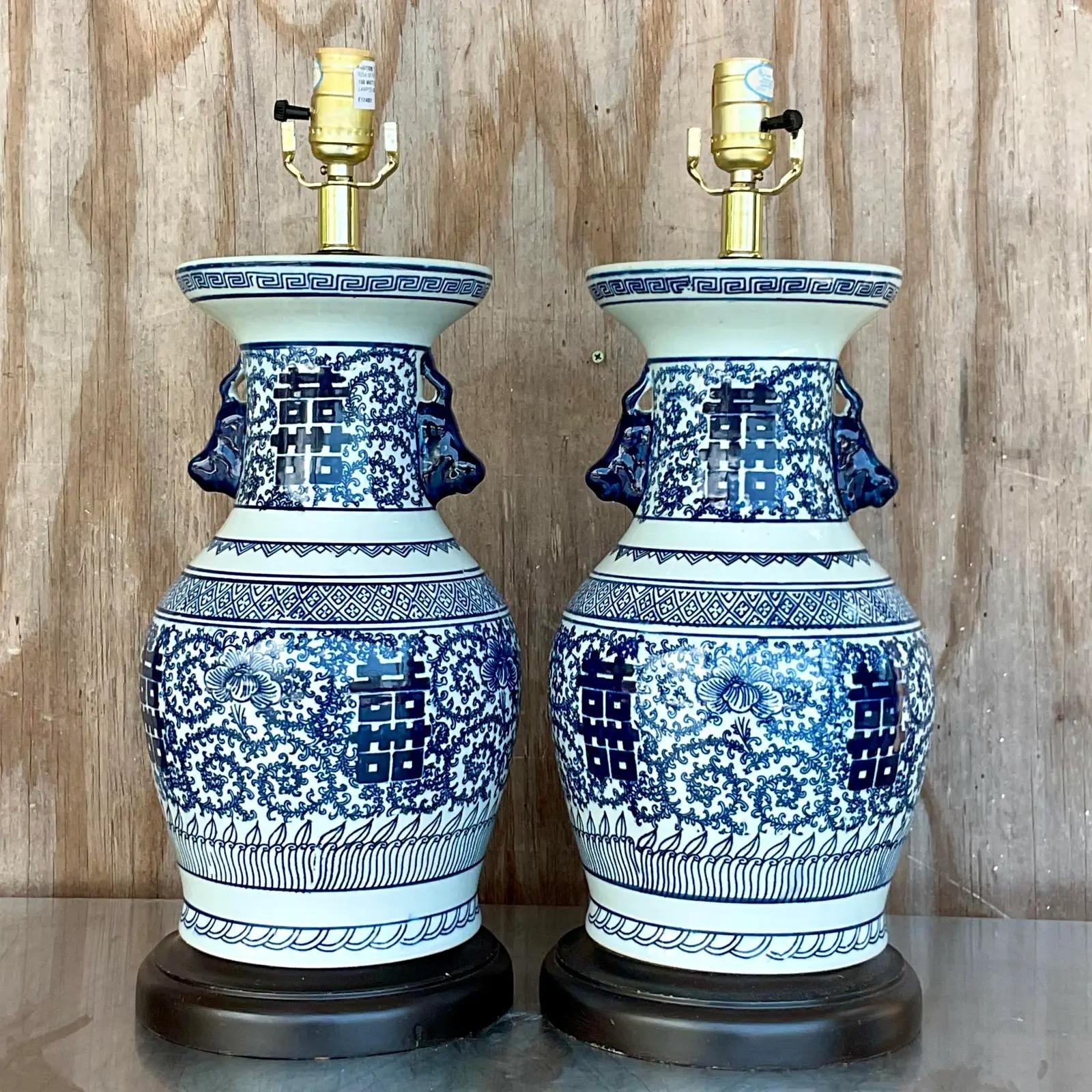 Fantastic pair of vintage table lamps. Classic blue and white design with Asian characters on a Ming base shape. Rest on wooden plinths. Acquired from a Palm Beach estate.

The lamps are in great vintage condition. Minor scuffs and blemishes