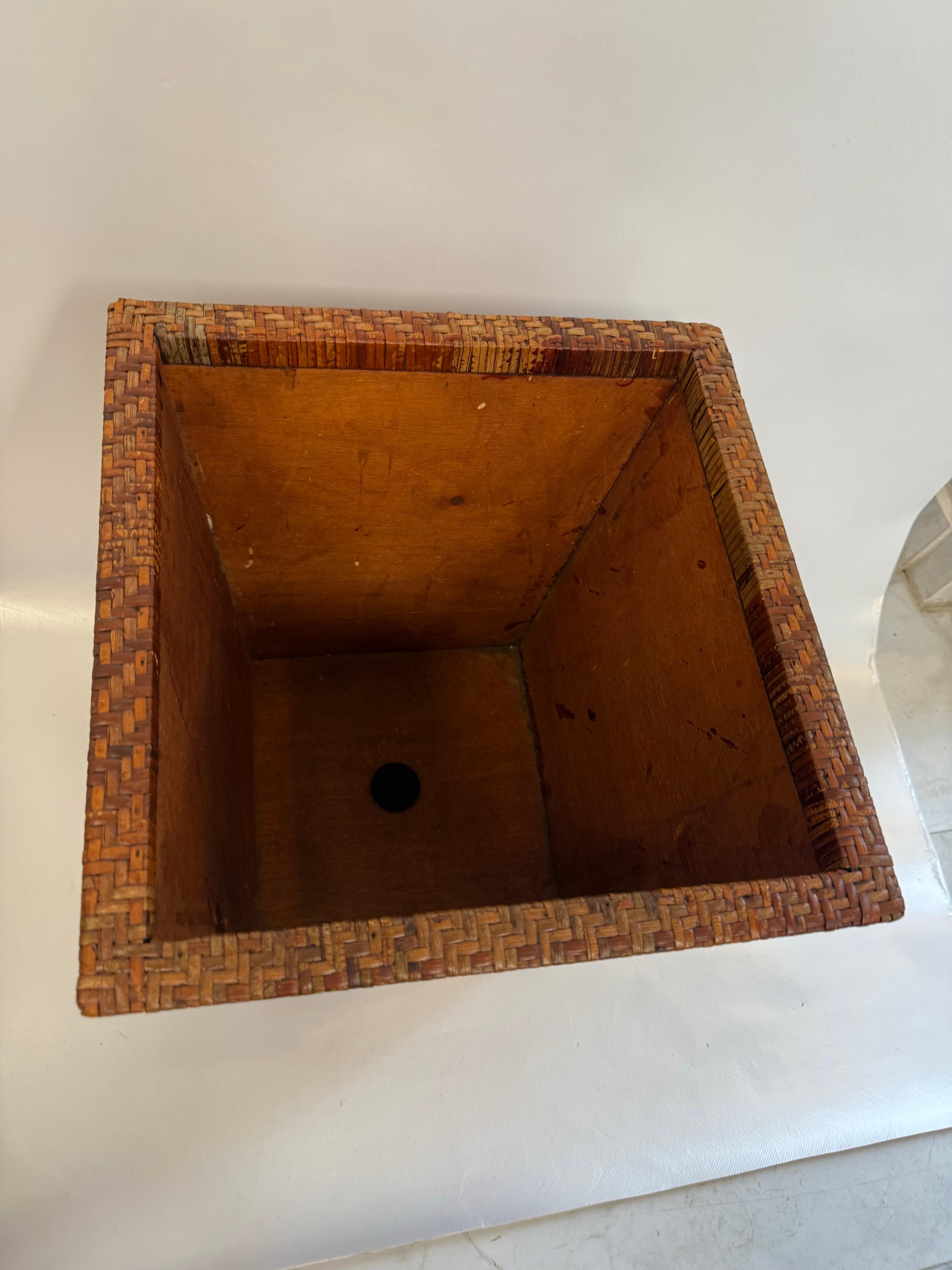 Une jardinière unique de style asiatique du milieu du siècle avec de l'osier tressé autour du sommet, des bandes de bambou coupées sur les côtés, et un fond et un intérieur en bois massif.   

Vintage Asian Boho Chic Wicker Rattan Teak Wood Square