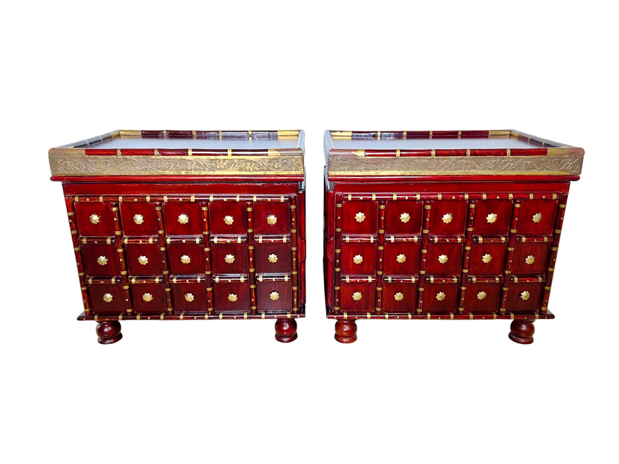 An interesting and finely crafted pair of mid 20th century Indo Asian brass clad side or end tables. Constructed of lacquered wood (likely mahogany and teak) and finished on all sides, they feature a lipped top edge, framed paneling and bun feet.