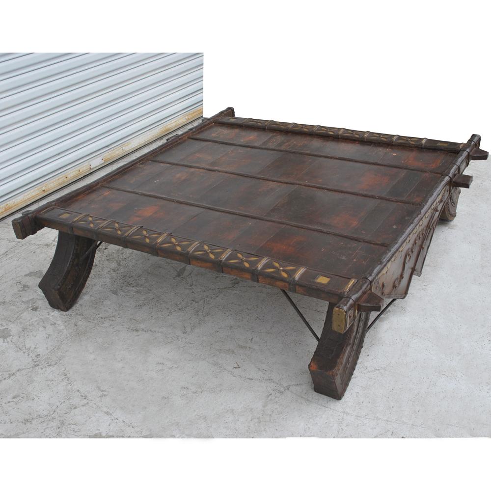 Vintage Asian bullock cart coffee table 

Originally an ox cart from Asia that has been 
converted into a coffee table. 
Aged teak with iron fittings and brass details. 
Carved legs and sides.