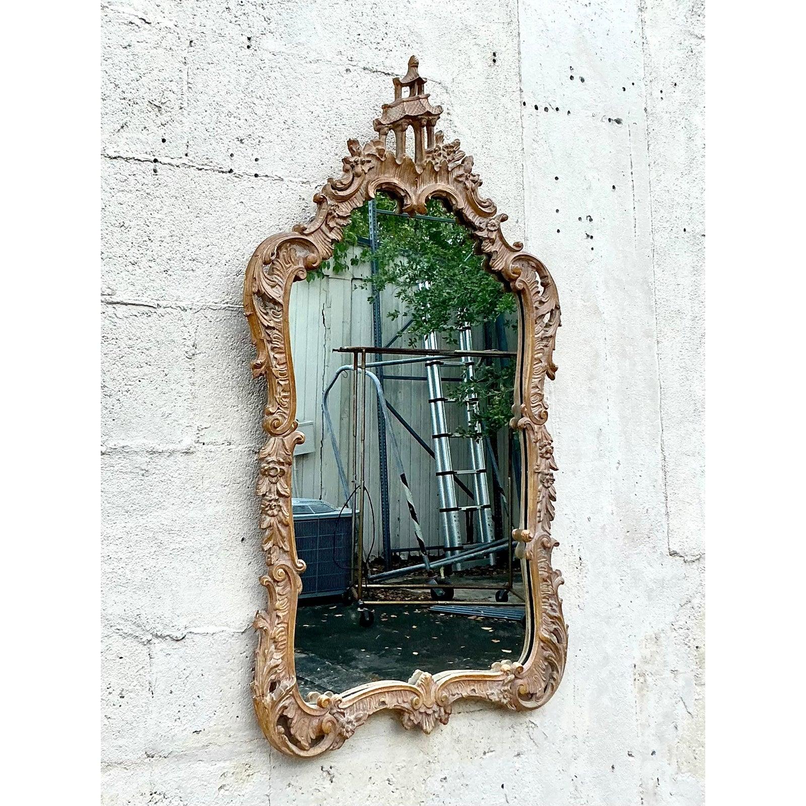 Élevez votre espace avec cet exquis miroir vintage, magnifiquement sculpté dans un style Chinoiserie avec une crête de pagode complexe et des motifs botaniques florissants. Les feuilles d'acanthe enroulées et les délicats détails floraux du cadre