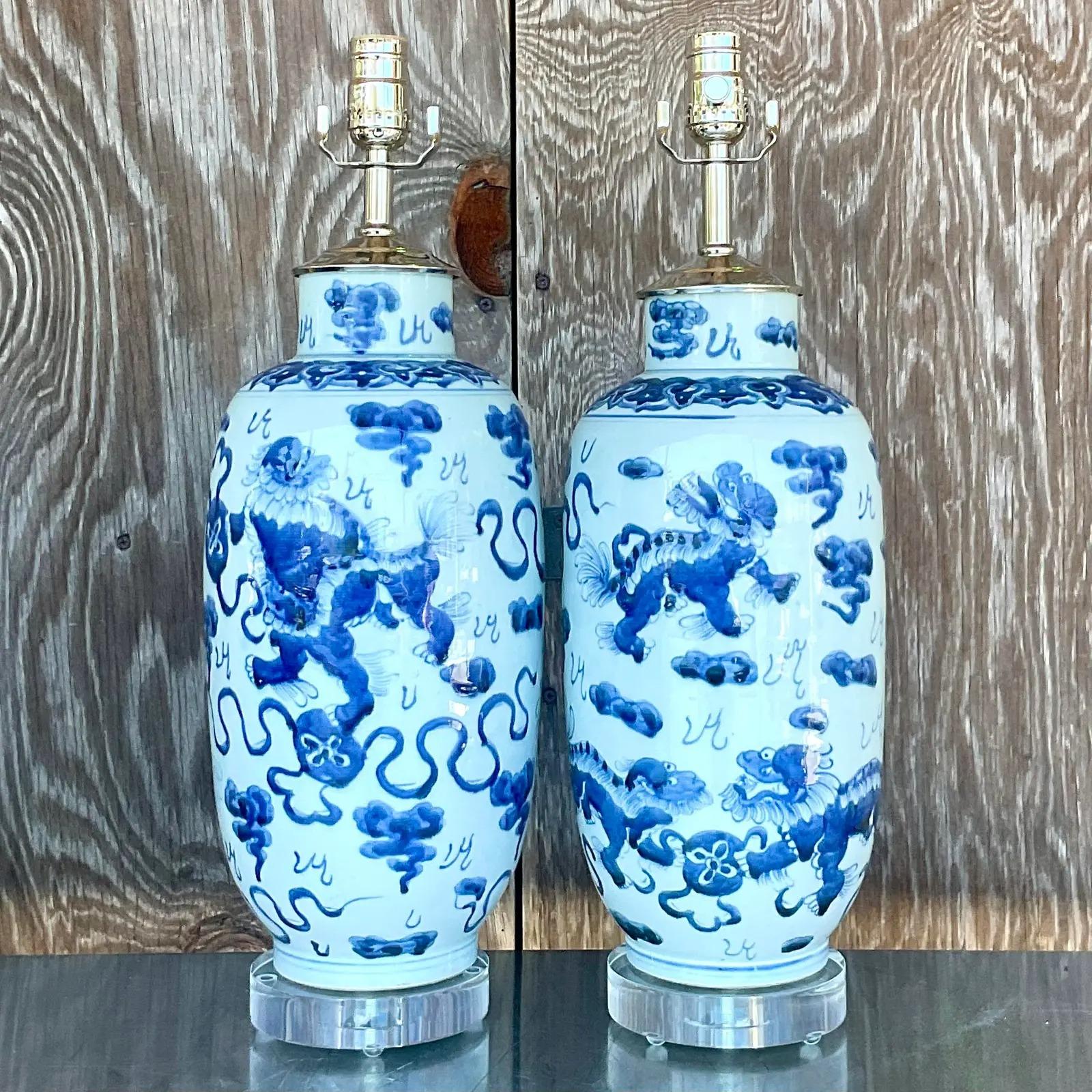 Fantastic pair of vintage Chinese blue and white table lamps. Beautiful Foo Dog design with a high gloss glazed finish. Fully restored with all new wiring, hardware and lucite plinths. Acquired from a Palm Beach estate.