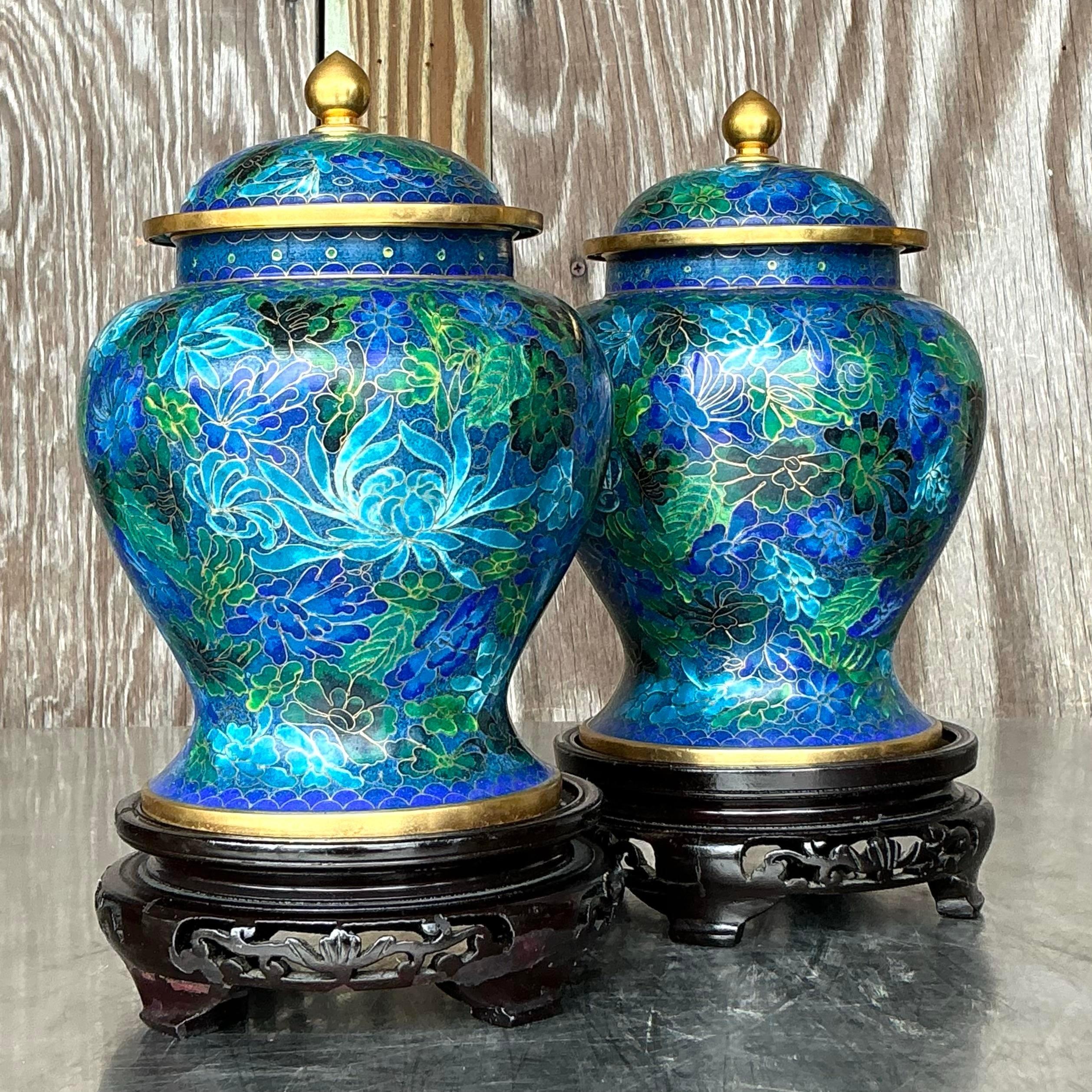 Aggiungi un tocco di eleganza esotica al tuo arredamento con questa splendida coppia di urne asiatiche vintage in cloisonné. Questi vasi dalla lavorazione intricata sono caratterizzati da vivaci disegni smaltati, che mostrano delicati motivi