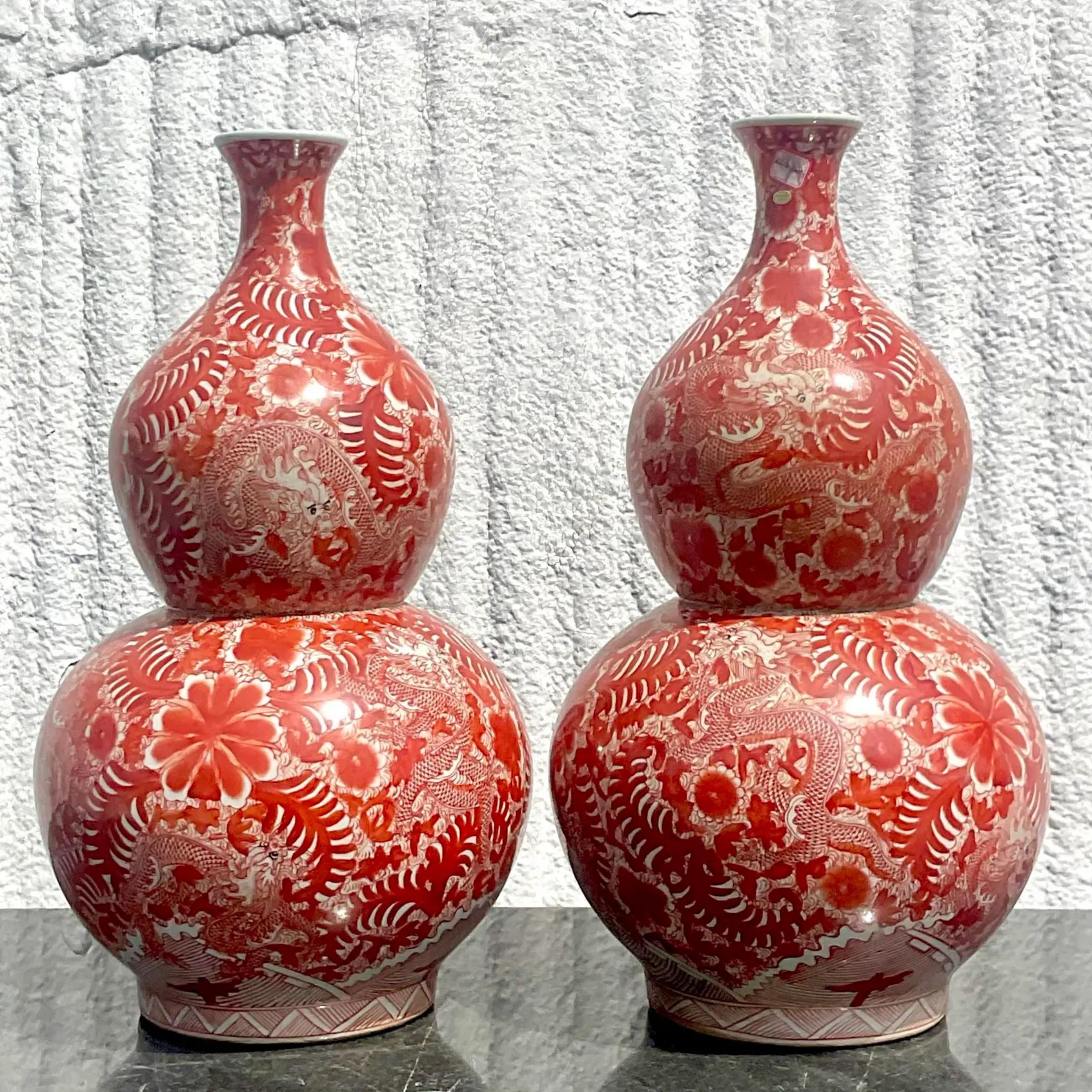 A pair of fabulous vintage Asian vases. This pair of Asian vases are in a beautiful shade of red with amazing details of dragons and flowers. It is an amazing piece to add to any room. Acquired in a Palm Beach estate.
