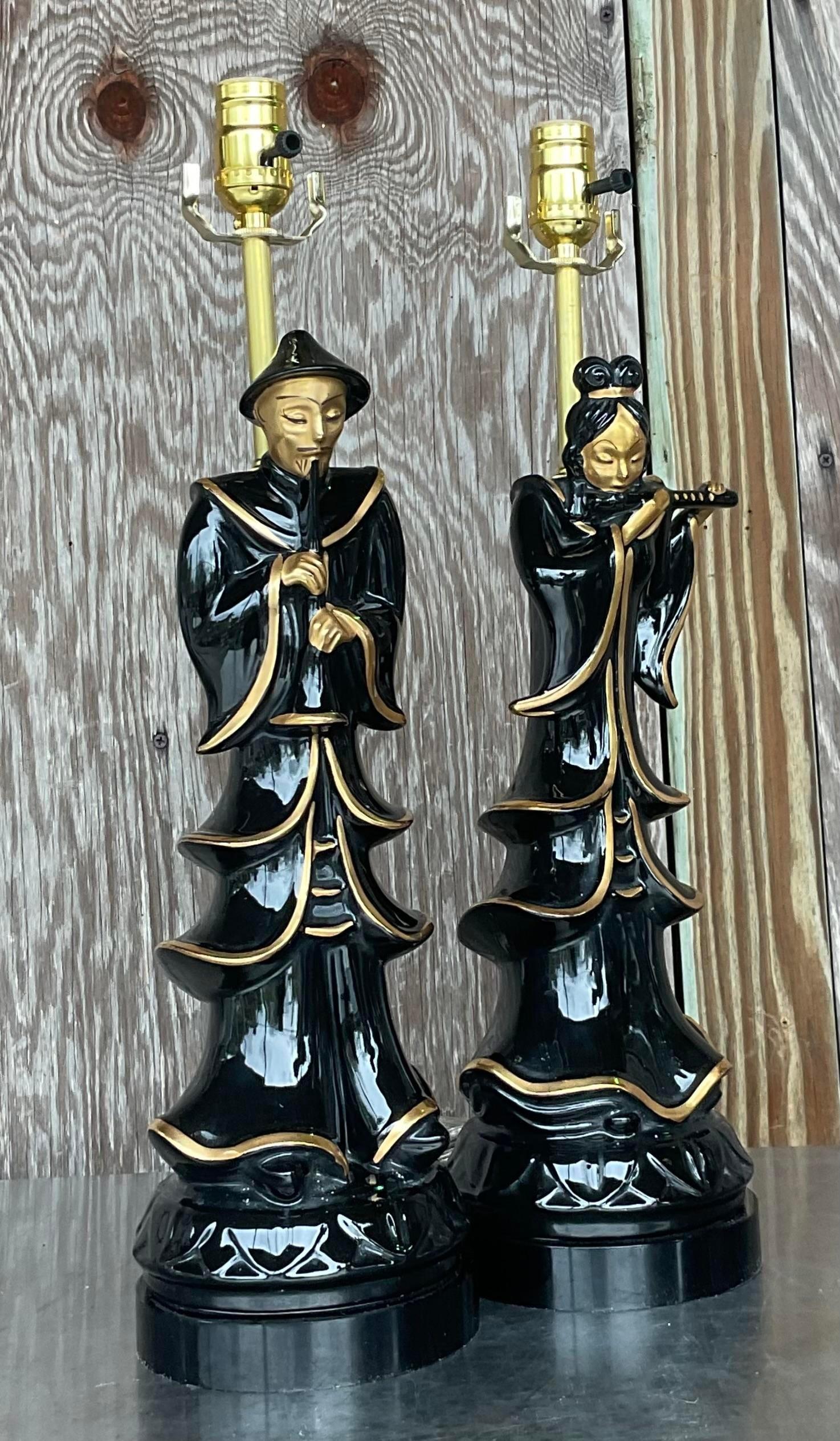 A fabulous vintage Asian pair of lamps. A glamorous Emperor couple in a sleek black glazed ceramic with gilt touches. Fully restored with all new wiring, hardware and black lucite plinths. Acquired from a Palm Beach estate.

Smaller lamp is 5x5x21