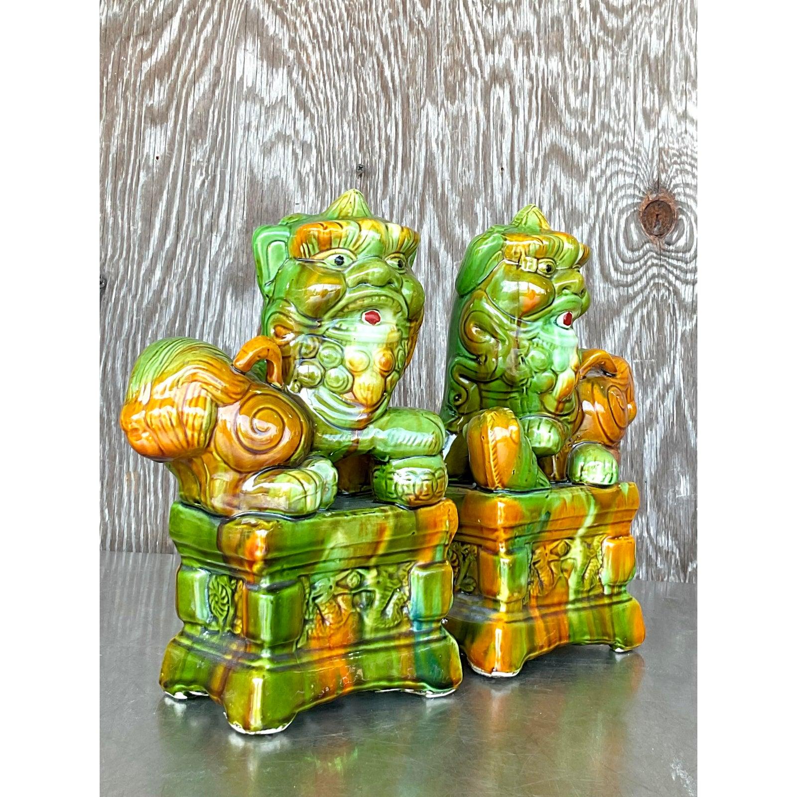 Add a striking touch of heritage and symbolism to your space with this vibrant pair of vintage Asian ceramic Foo Dogs. Masterfully glazed in rich tones of green, amber, and golden brown, these protective guardian lions exude bold energy and timeless