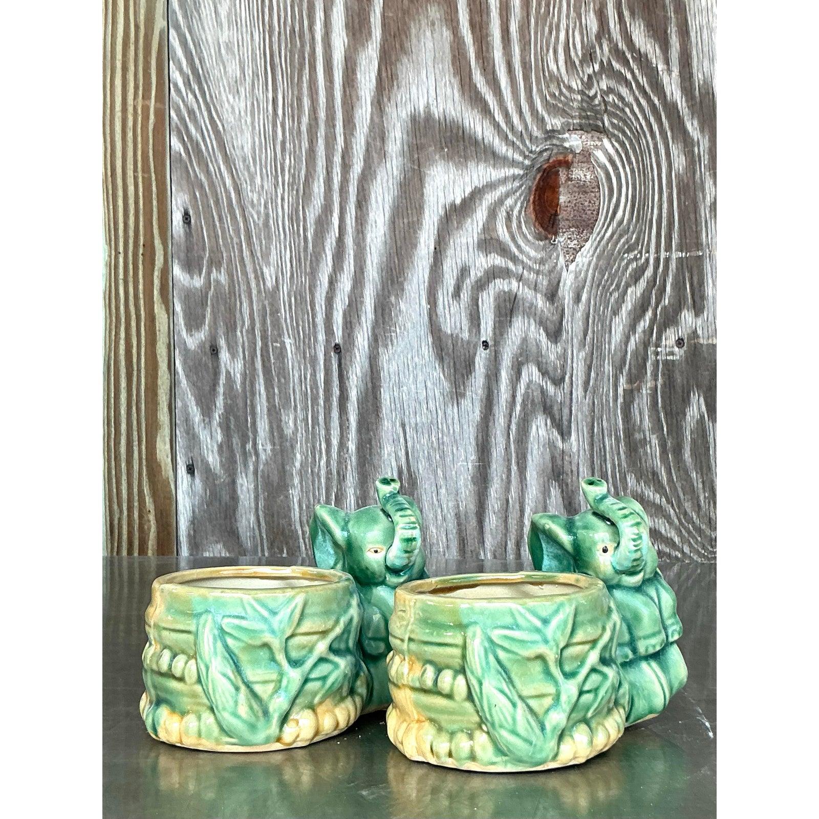 Dai un tocco di esotismo al tuo arredamento con questa affascinante coppia di fioriere vintage a forma di elefante asiatico. Realizzata in ceramica smaltata nei toni del verde, ogni fioriera presenta un elefante dolcemente dettagliato con la