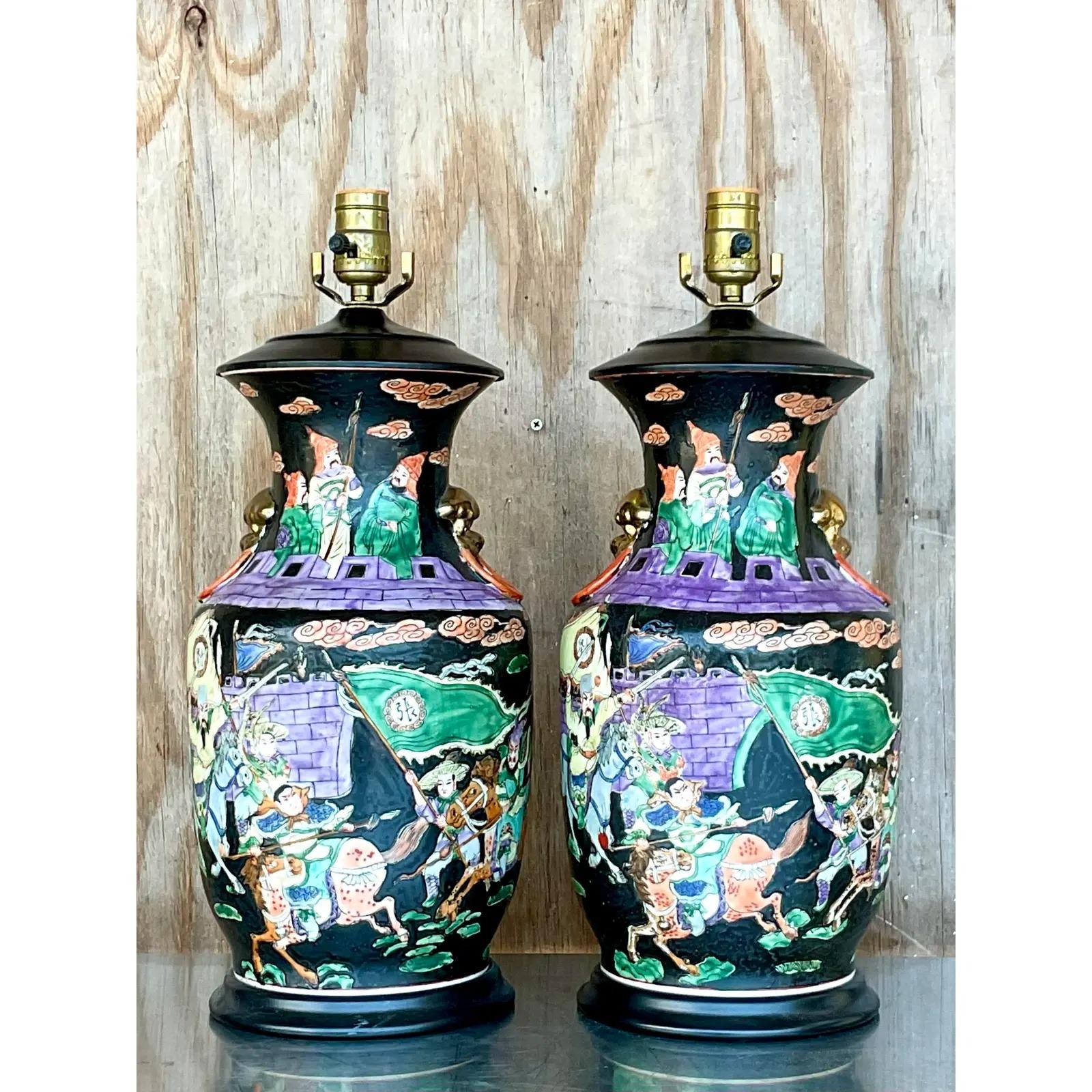 Stunning pair of vintage Asian ceramic lamps. Beautiful jewel tone composition in classic Chinoiserie scenes. Acquired from a Palm Beach estate.