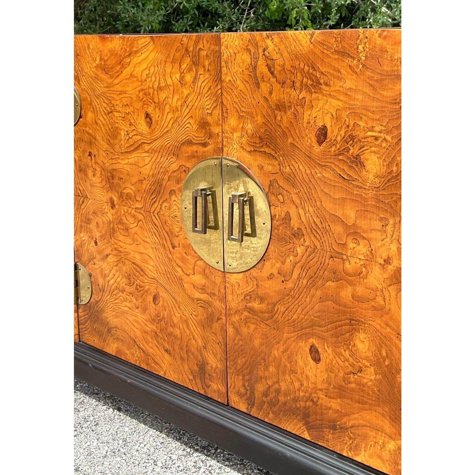 Add a touch of refined exoticism to your space with this vintage Asian-inspired burl wood low credenza, featuring striking brass medallion hardware and richly grained veneer. The symmetrical four-door design is elevated by gleaming round brass