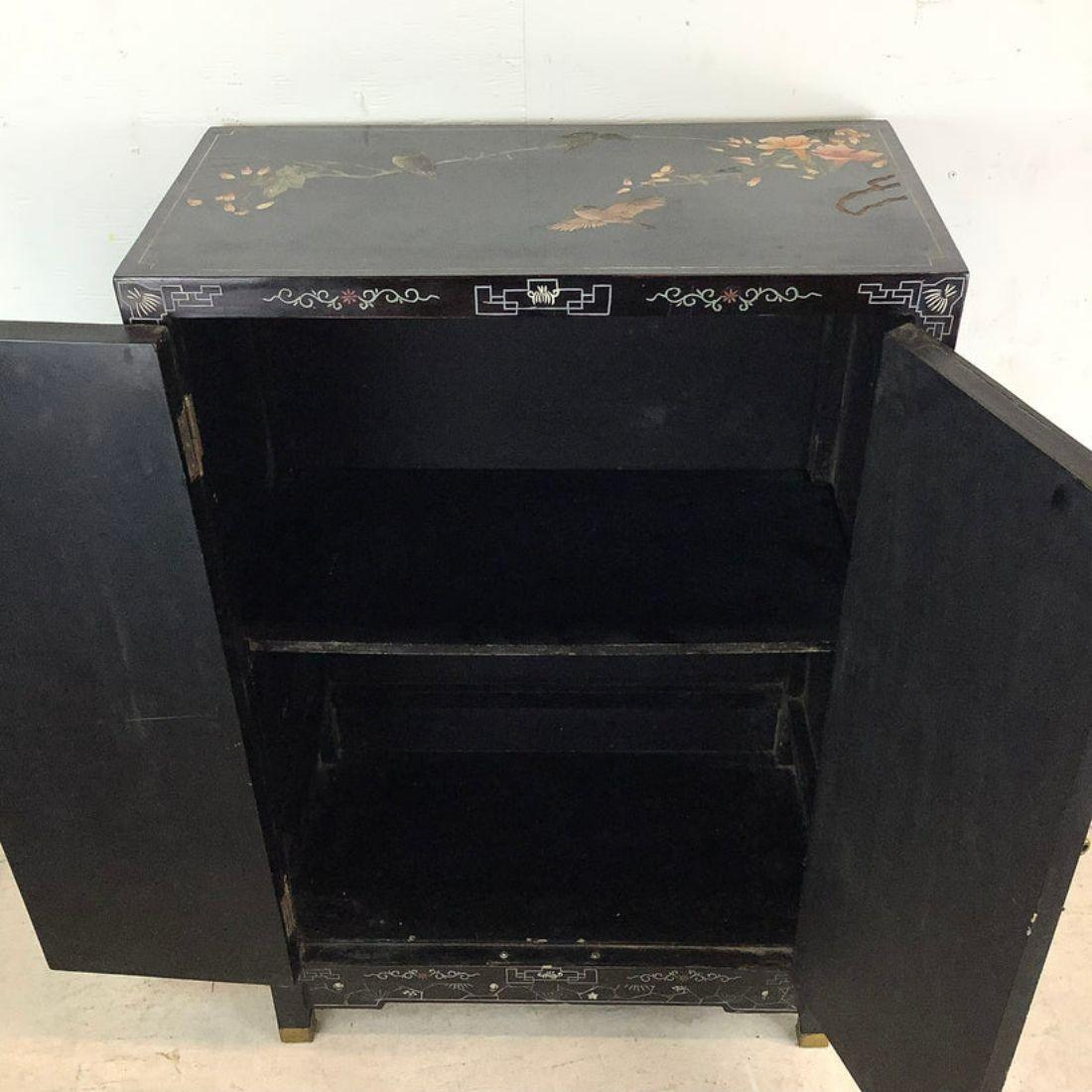 This striking Asian modern storage cabinet features black lacquer finish with illustrated designs and inlays. The decorative nature of this ample sized cabinet makes it an impressive addition to any setting while the shelved interior makes this a