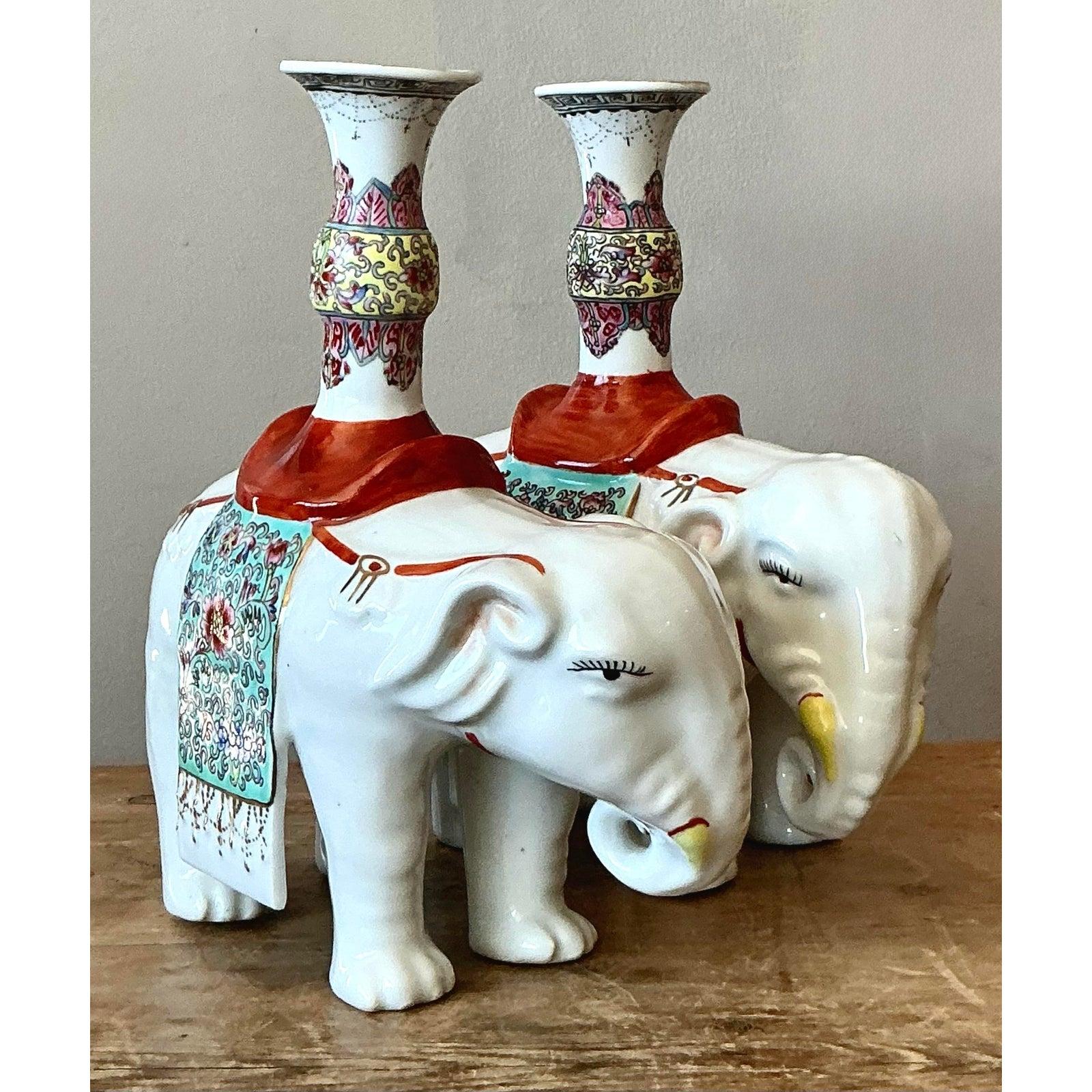 Cette paire captivante de figurines d'éléphants en céramique vintage rend hommage à la tradition classique de la Chinoiserie, conçue pour servir d'objets décoratifs saisissants ou de bougeoirs majestueux. Chaque éléphant est réalisé en porcelaine
