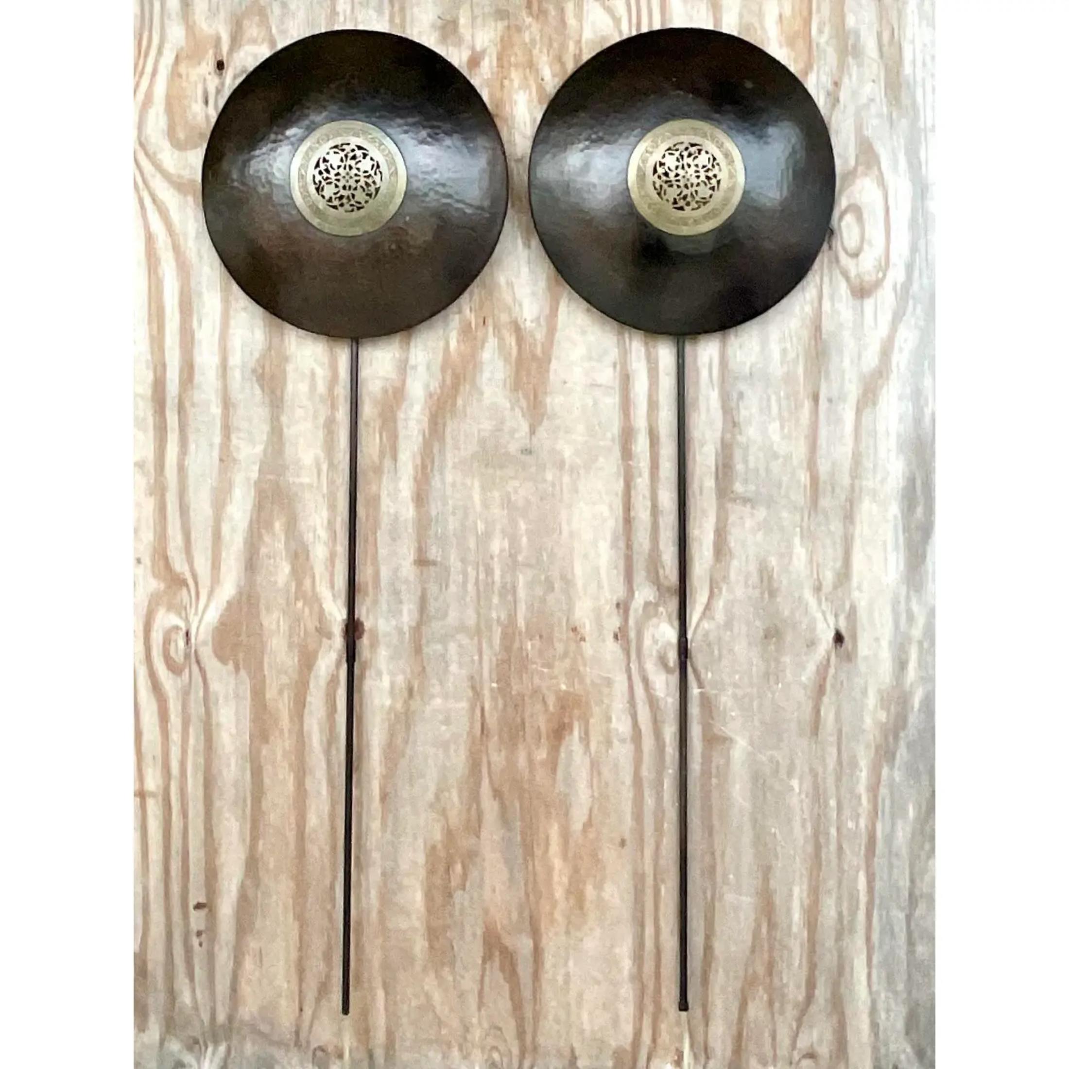 A fabulous pair of vintage Asian wall sconces. A chic Asian Medallion design with a patinated brass finish. 3ft metal rod holds the plug. Acquired from a Palm Beach estate