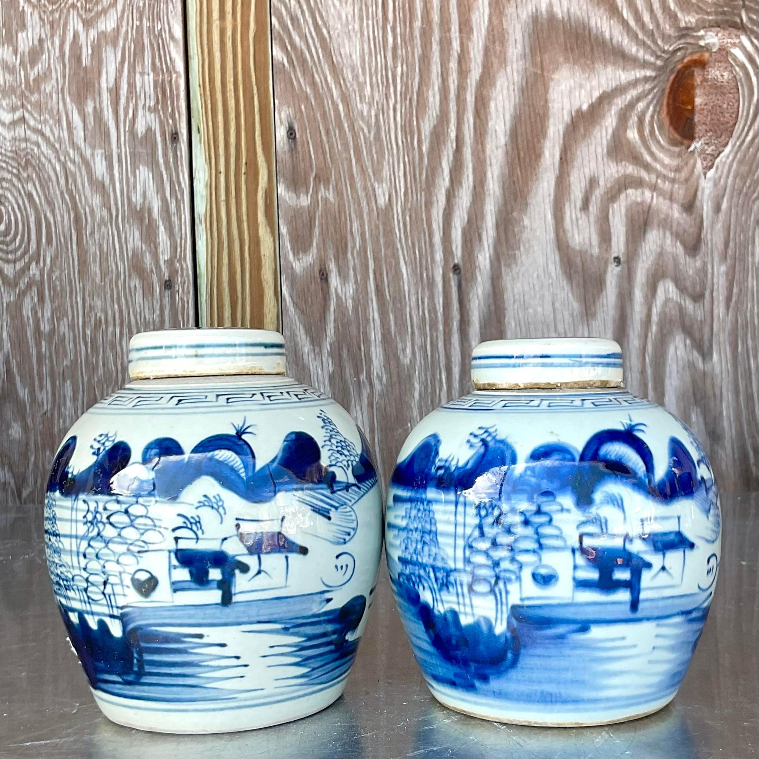 A fabulous pair of vintage petite ginger jars. A charming pair of blue and white vessels with a classic Asian motif. Each has its own lid. Unsigned. Acquired from a Palm Beach estate.