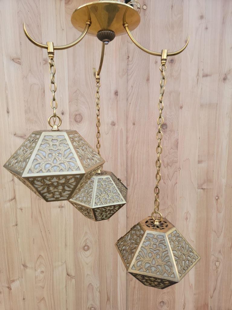 Vintage Asian Pierced Brass Trio of Multi Tiered Ceiling Pendant Chandelier 

Vintage Asian pierced, brass hanging trio of multi-tiered 3-pendant light chandelier with a scrolling arabesque patterned motif. 

Handcrafted in Japan from thick