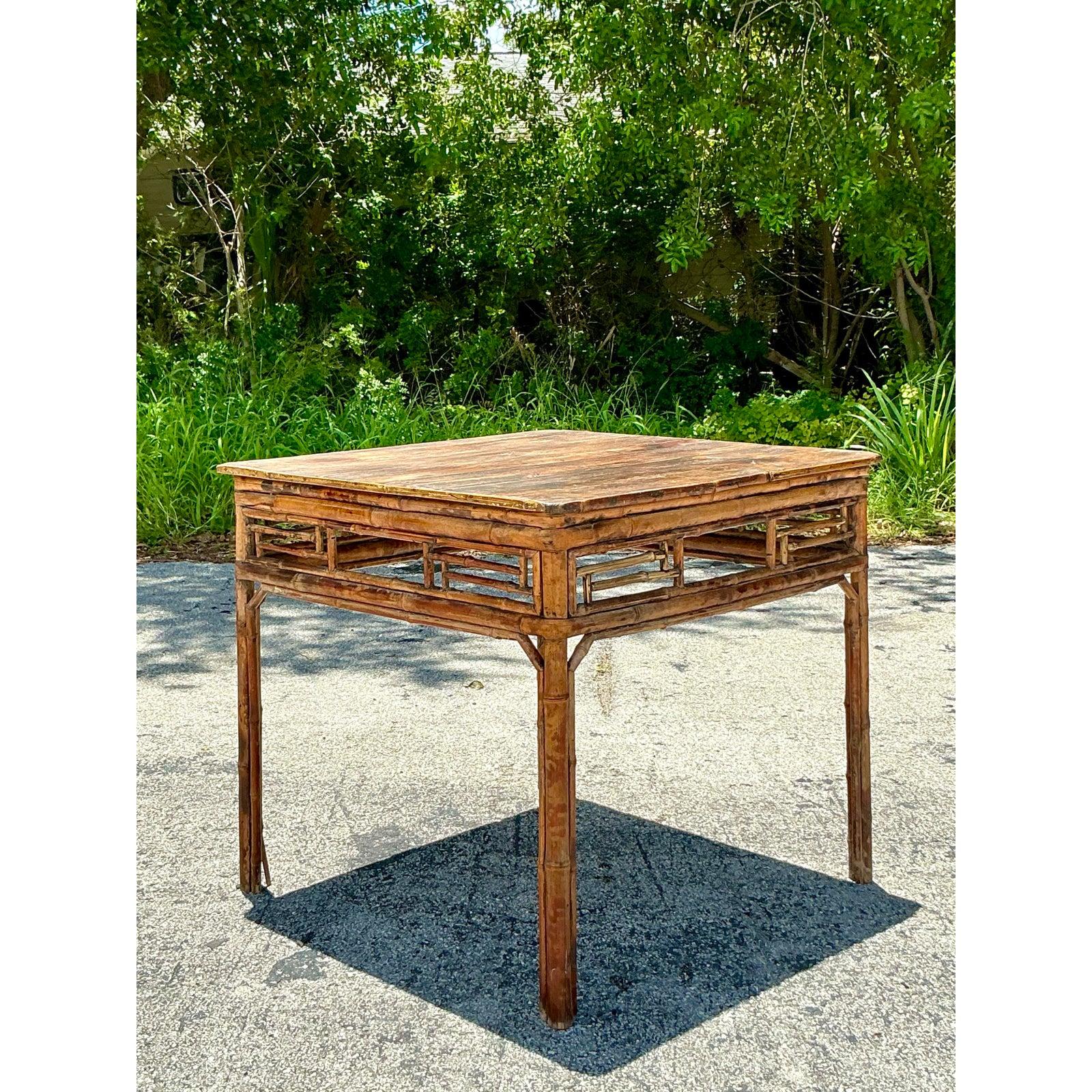 Infondi nel tuo spazio lo stile Chinoiserie con questo splendido tavolo da gioco vintage in bambù e legno. La caratteristica principale del tavolo è la sua base in bambù sapientemente lavorata a mano, che vanta un intricato traforo geometrico lungo