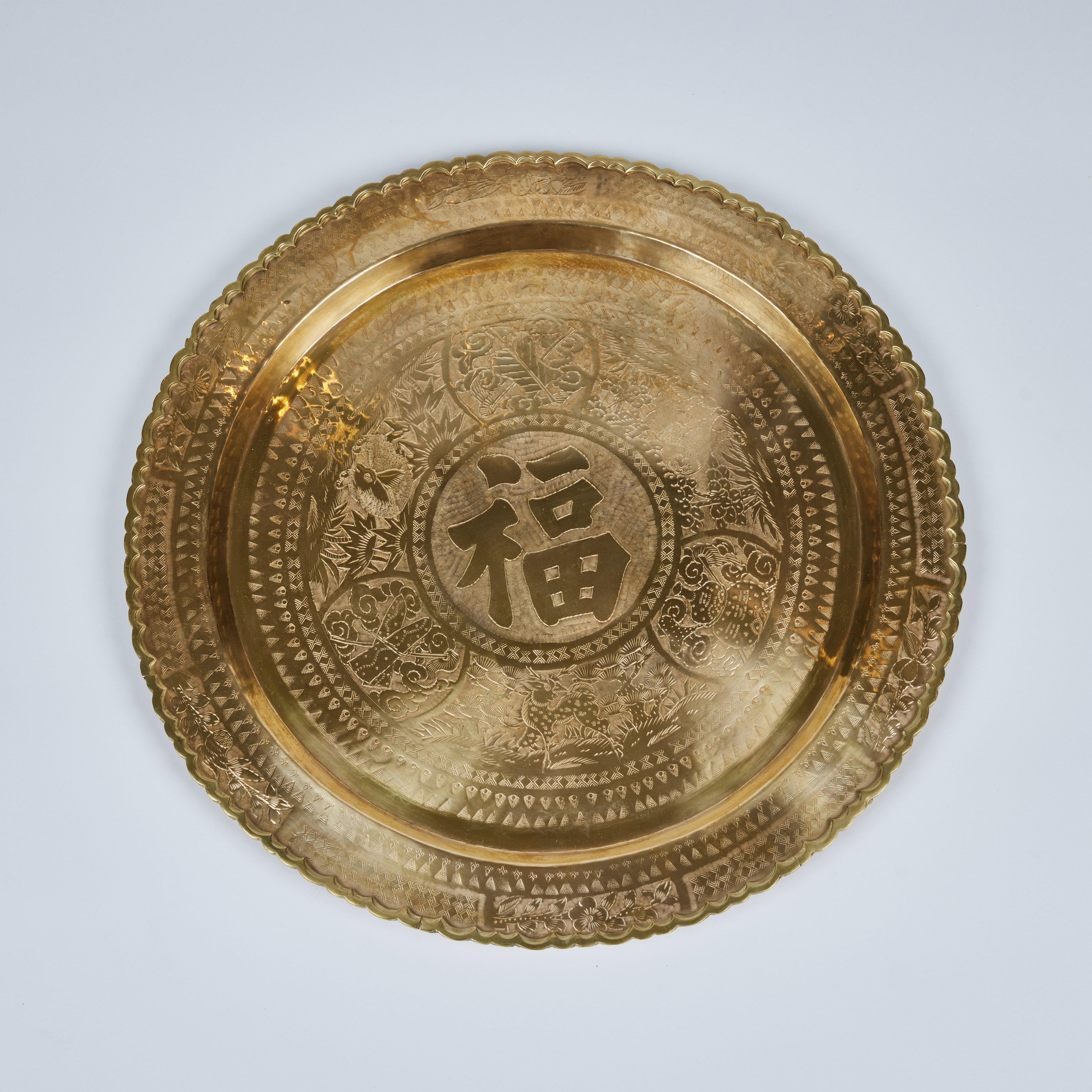 Brilliant vintage Asian round brass serving tray is decorated with intricate hand etched detailed floral, patterned and calligraphic designs. It has an ornamental 3 dimensional attached scalloped edge border and has been newly polished. It measures