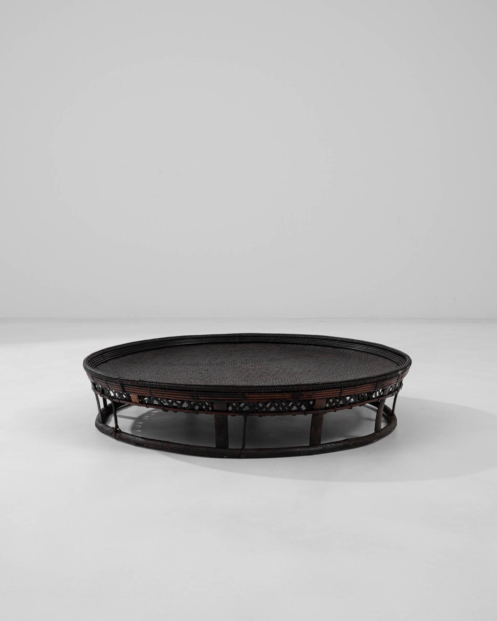 A wooden coffee table created in Asia during the 20th century. Low, circular, and dark, this exquisite coffee table emits an enigmatic charisma that draws one toward it. Composed of circularly bent wooden splints, an ample circle has been expertly