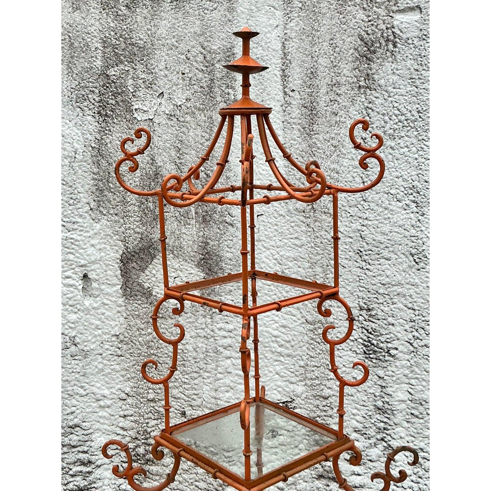 Introduce an enchanting touch of Chinoiserie elegance to your interior with this delightful vintage wrought iron pagoda etagere. Its iconic tiered structure, crowned with a whimsical pagoda top and adorned with graceful scrolls and faux bamboo