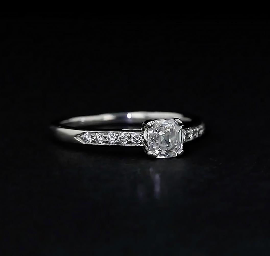 Dieser klassische und doch moderne antike Verlobungsring aus Platin hebt einen spektakulären Asscher-Diamanten hervor, der auch als quadratischer Smaragdschliff bekannt ist und 0,80 Karat wiegt. Der Mittelstein wird durch weitere 0,30 Karat runder