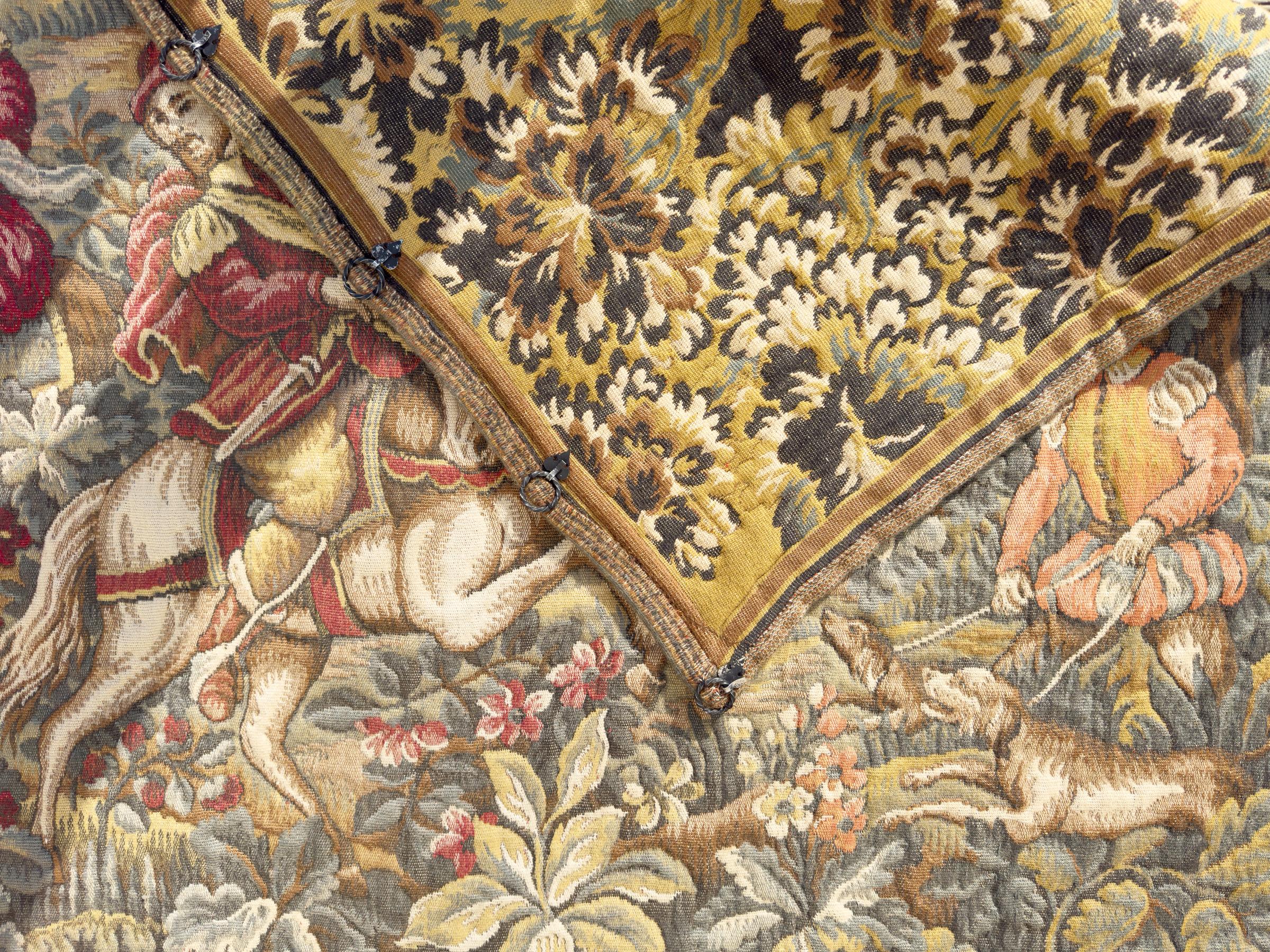Cette tapisserie jacquard française vintage, probablement réalisée dans les années 1940 dans le style d'Aubusson, présente une scène de chasse richement détaillée. Tissée à Halluin, une région réputée pour son artisanat textile, la tapisserie
