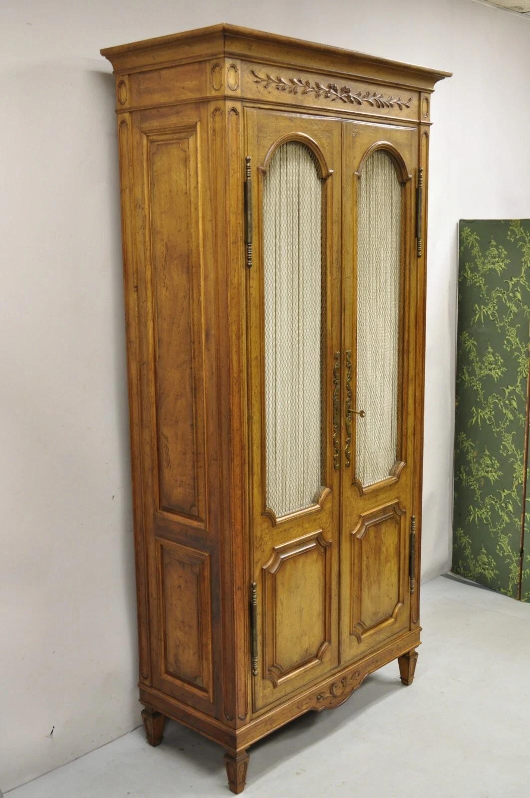 Vintage Auffray & Co French Country Provincial Tall Sculved Fruitwood Armoire Cabinet Wardrobe. Le Label se caractérise par une construction en bois massif, une finition antiquaire/détresse, 2 portes battantes avec des façades en fil métallique, des