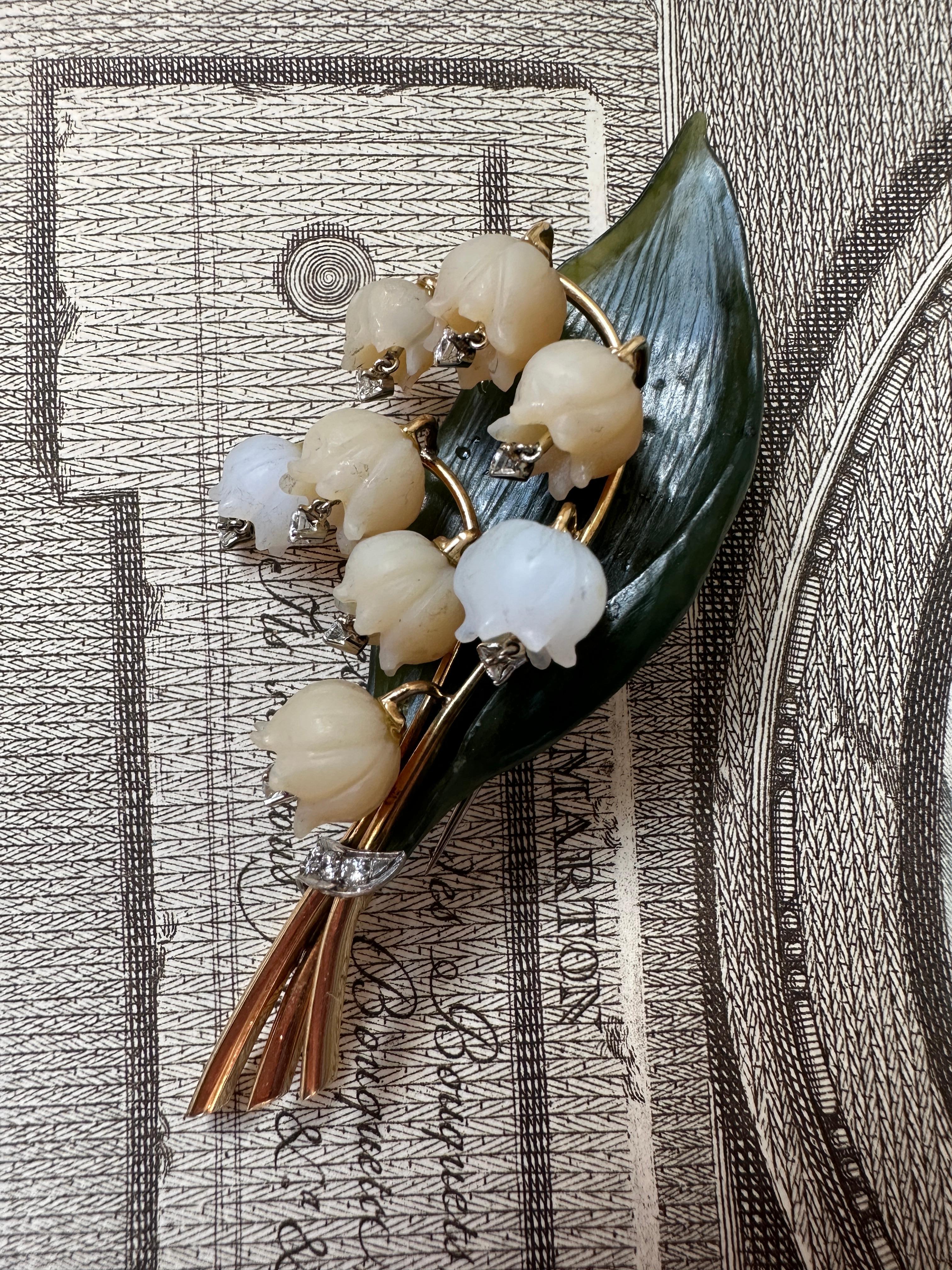 A lovely vintage brooch realistically modeled as a stalk of lily of the valley, set with frosted carved rock crystal flowerheads, each suspending a sparkling full cut diamond, to a carved serpentine leaf. Austrian hallmarks. C 1950

Measurements: 3