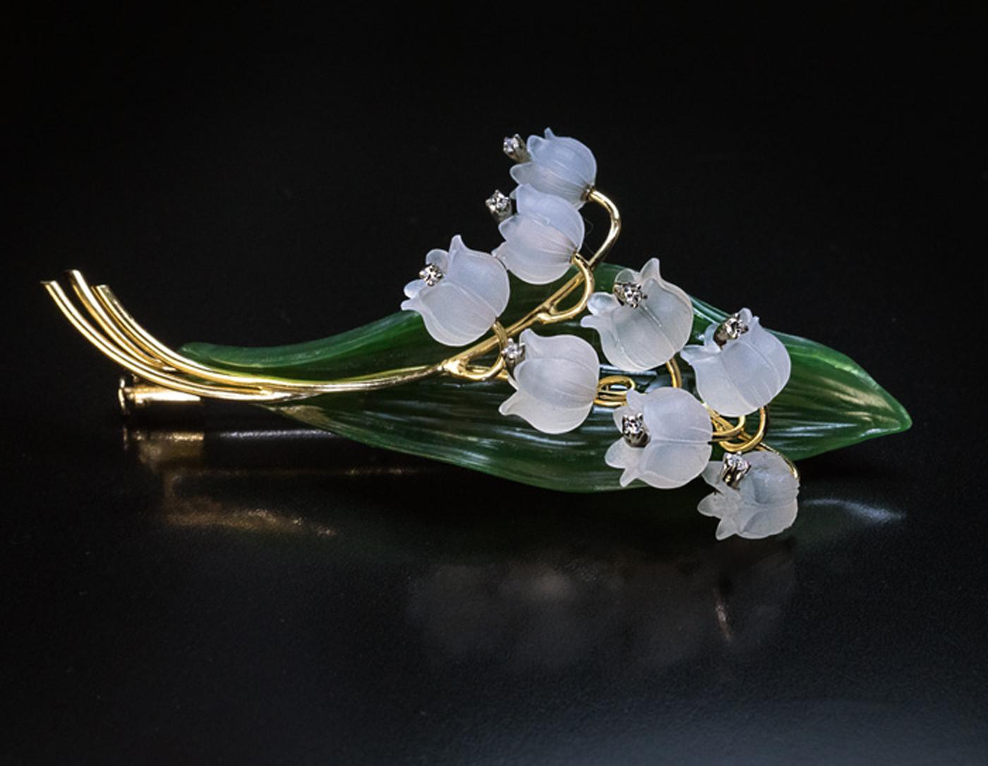 This large, finely modeled, hand carved nephrite jade and frosted rock crystal lily of the valley brooch / pin was made in Vienna, Austria in the 1950s. The flower is mounted in 18K yellow gold.

Each flower head is accented with a diamond.

Marked