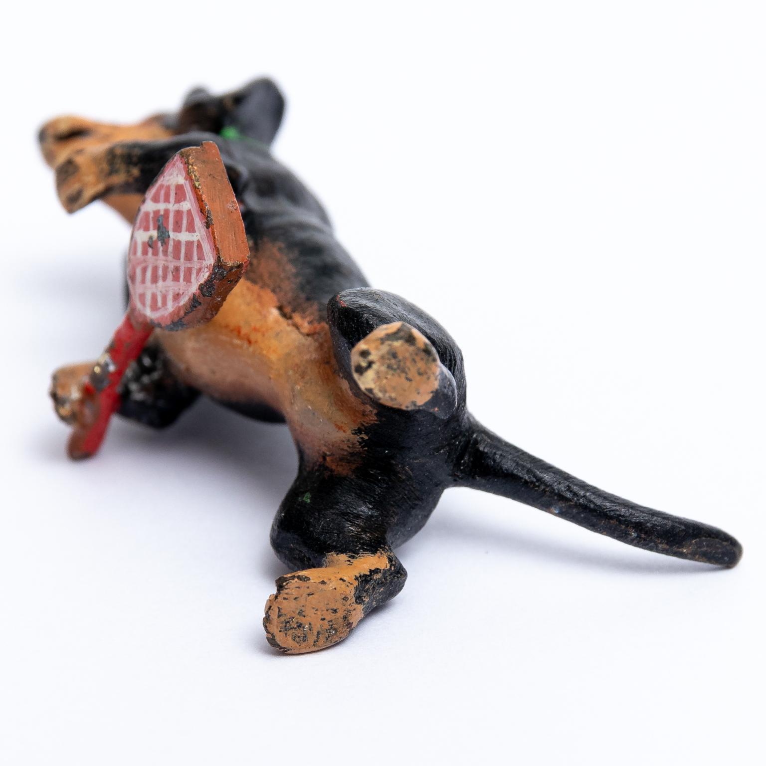 Circa 20th century Austrian cold painted bronze Dachshund dog figurine depicted playing a racket sport. Please note of wear consistent with age and use. The piece is unmarked. Made in Austria.