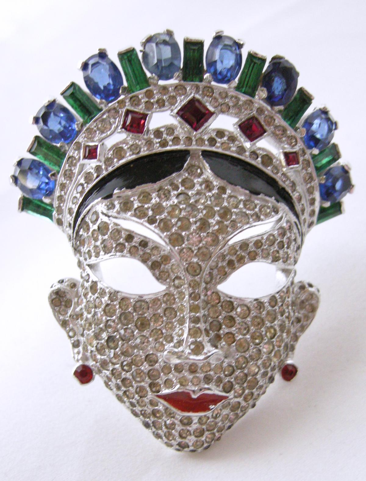 This is the famous original Mazer masked woman crystal face that is in the jewelry books.  Her crown has green and blue crystals.  Below are faux ruby crystals that are encrusted with crystals.  Black enamel separated the crown from the face.  The