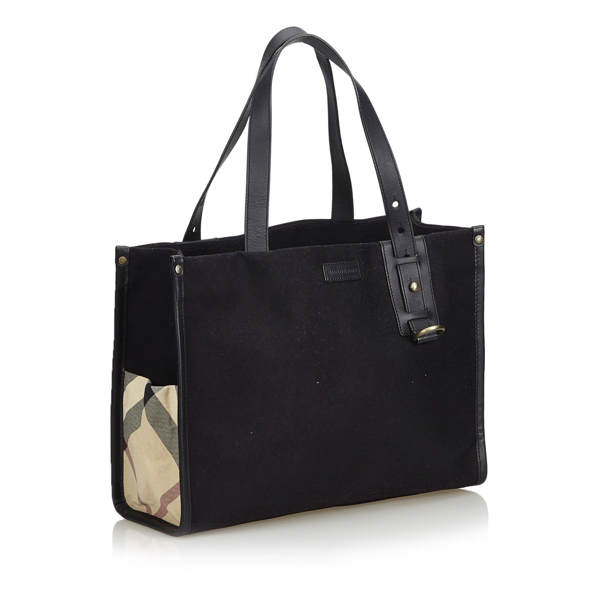This tote bag features a canvas body with leather trim, side nova check detail, flat leather handles, an open top, and interior zip and slip pockets. It carries as AB condition rating.

Inclusions: 
This item does not come with