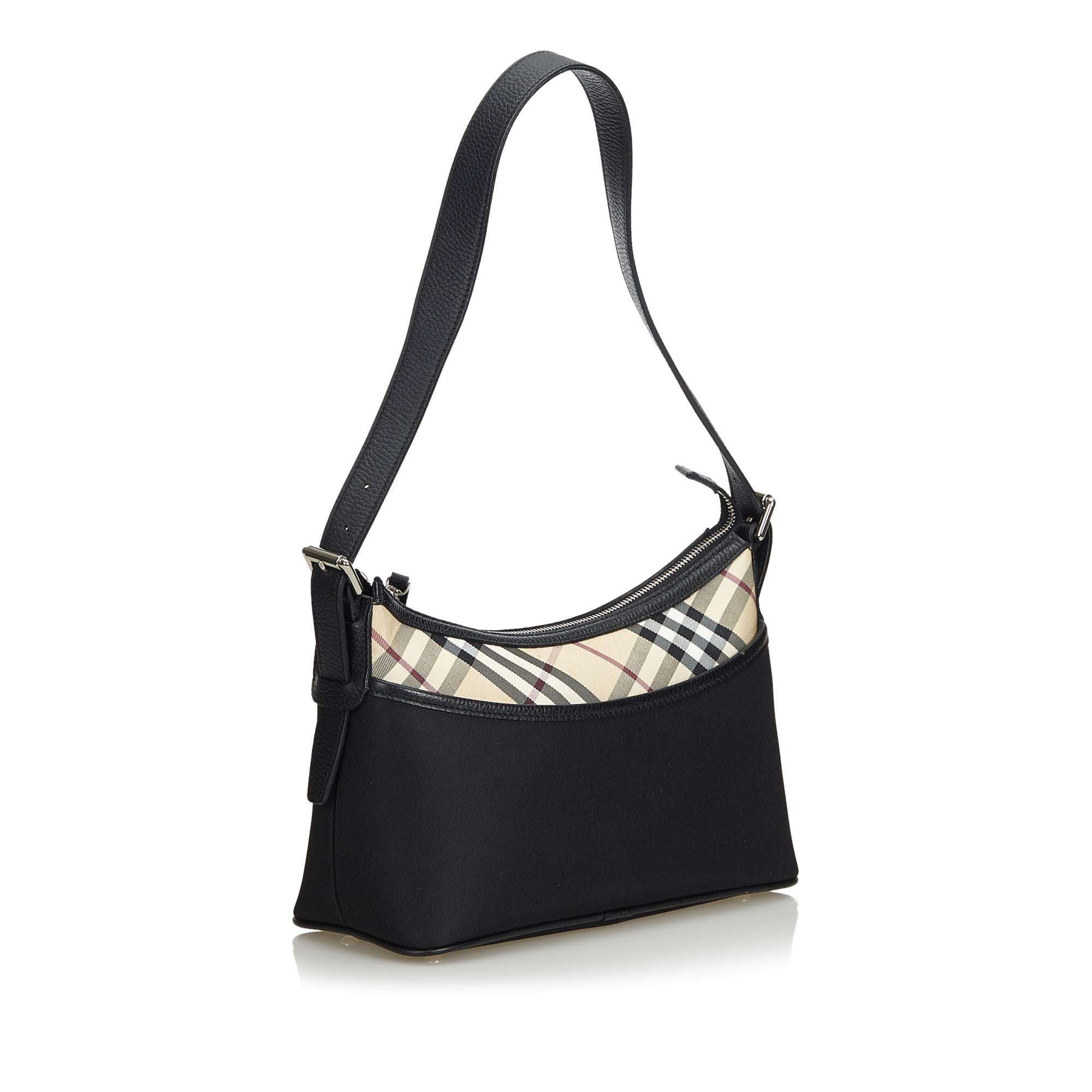 This shoulder bag features a nylon body with a nova check panel and leather trim, a front exterior slip pocket, an adjustable flat leather strap, a top zip closure, and interior zip and slip pockets. It carries as AB condition rating.

Inclusions: