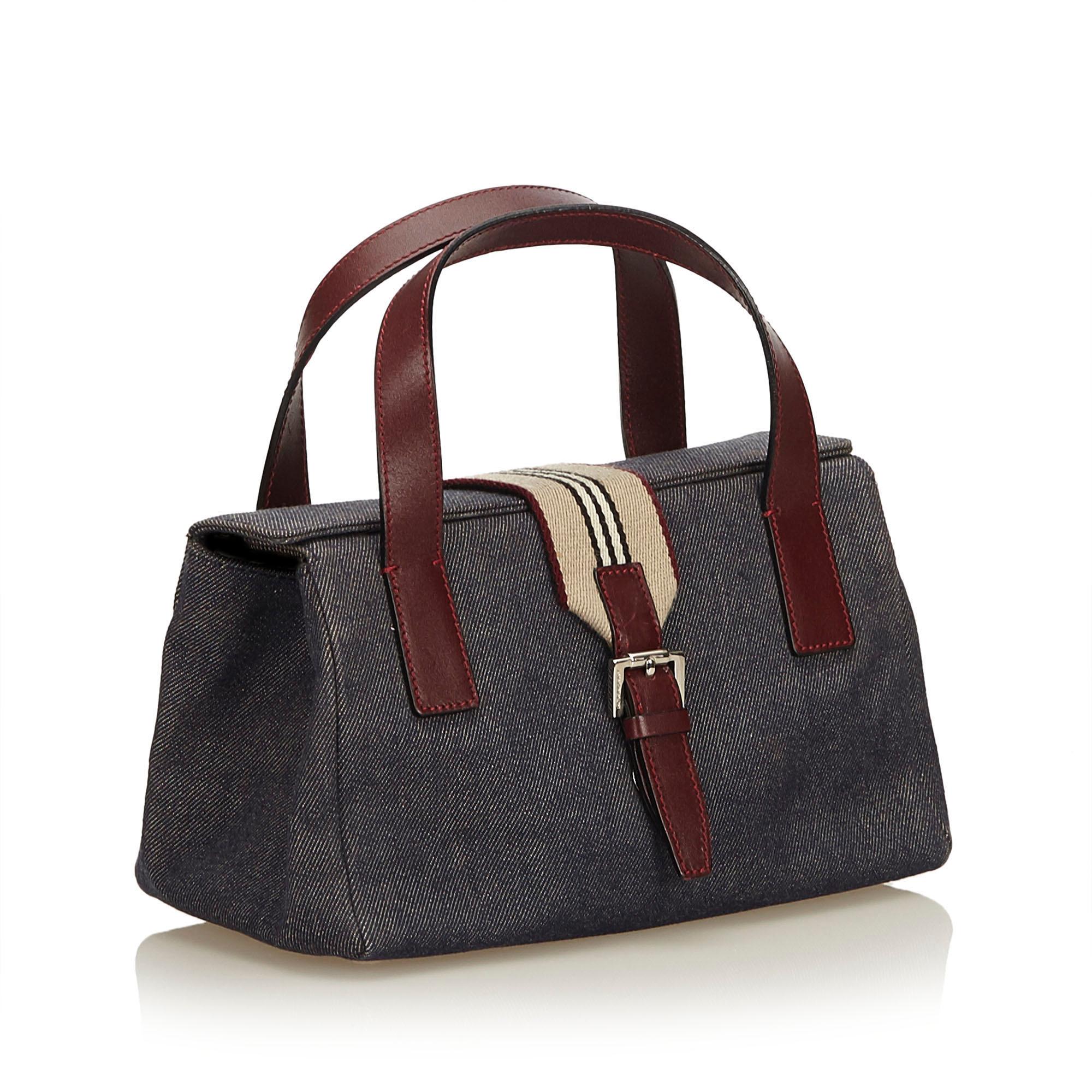 This handbag features a denim body, flat leather handles, top flap with front strap and magnetic closure, and an interior zip pocket It carries as B+ condition rating.

Inclusions: 
Dust Bag

Dimensions:
Length: 13.50 cm
Width: 24.00 cm
Depth: 13.50