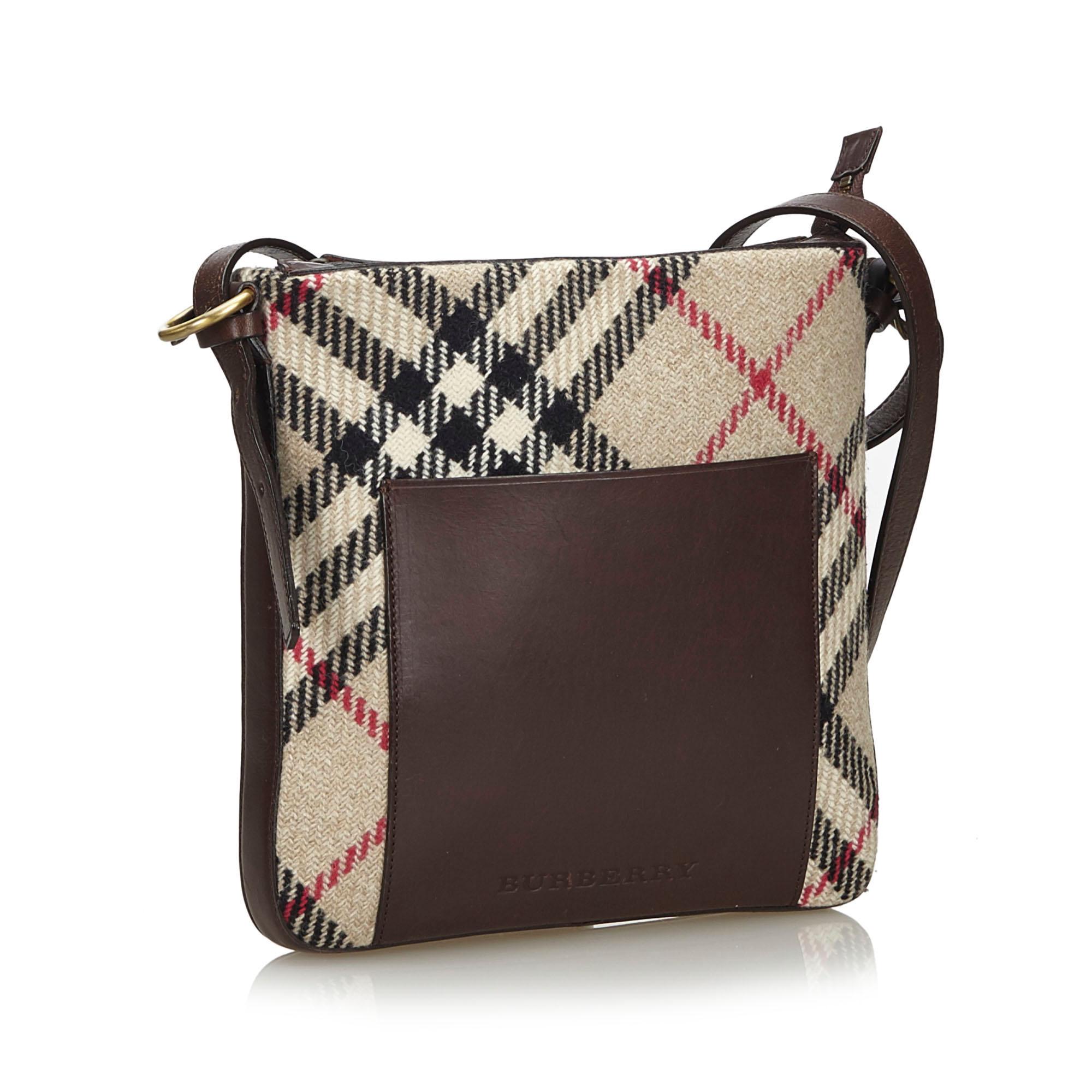 This crossbody bag features a plaid wool body with leather trim, a front exterior slip pocket, a flat leather strap, a top zip closure, and interior zip and slip pockets. It carries as AB condition rating.

Inclusions: 
This item does not come with