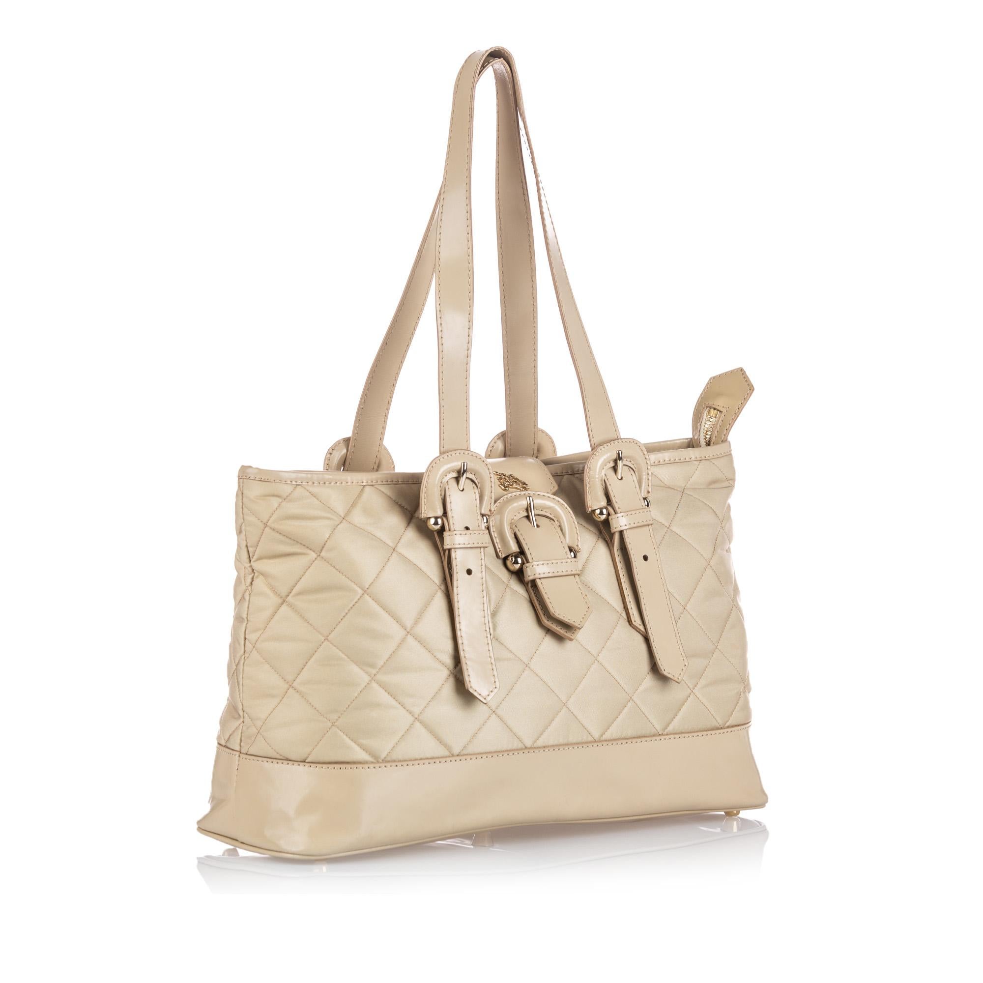 This tote features a quilted nylon body with leather trim, flat leather handles, a top strap with a buckle closure, a top zip closure, an interior zip and slip pockets. It carries as B+ condition rating.

Inclusions: 
This item does not come with