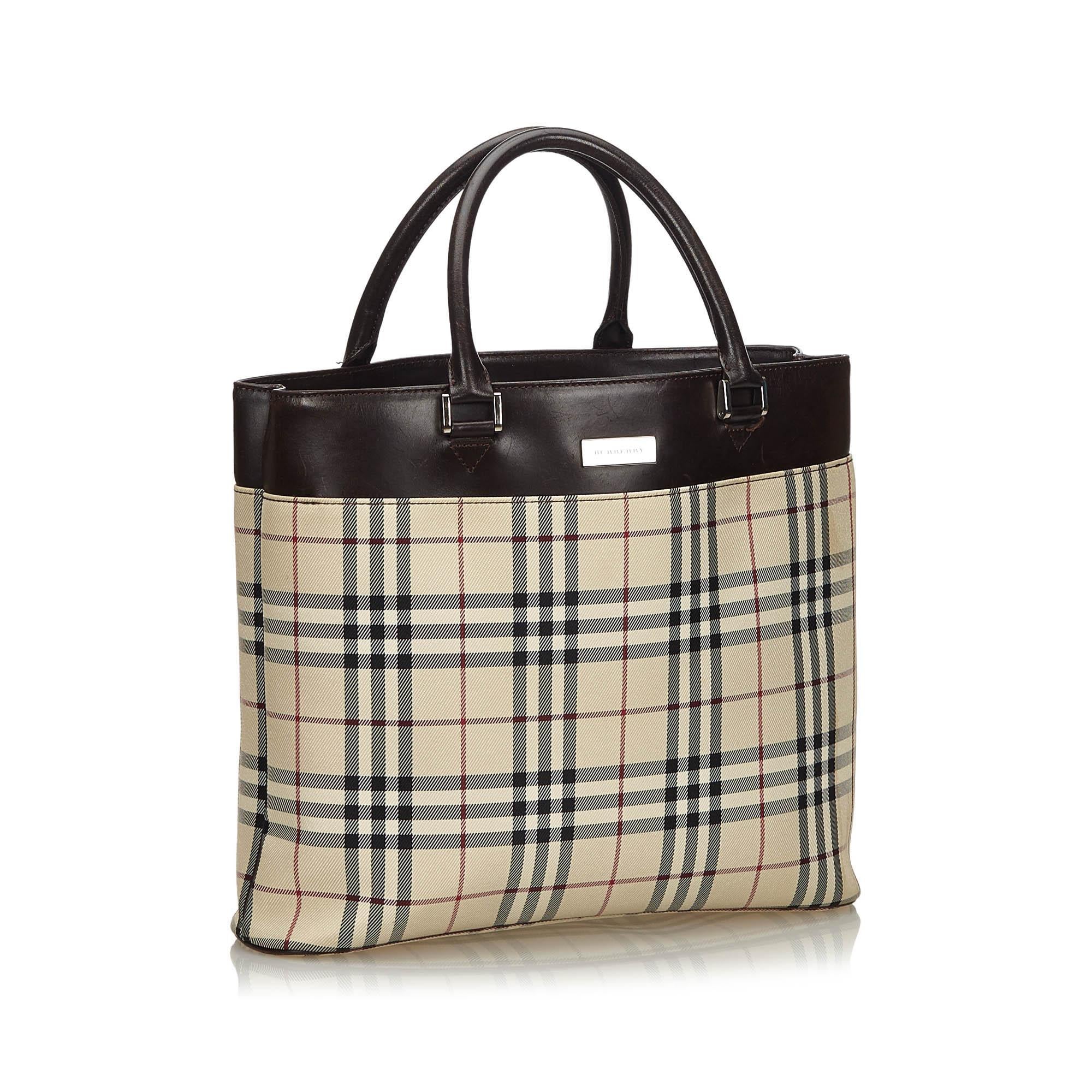 This tote features a plaid jacquard body with a top leather panel, an exterior slip pocket, rolled leather handles, a top magnetic closure, and interior zip and slip pockets. It carries as B+ condition rating.

Inclusions: 
Box

Dimensions:
Length:
