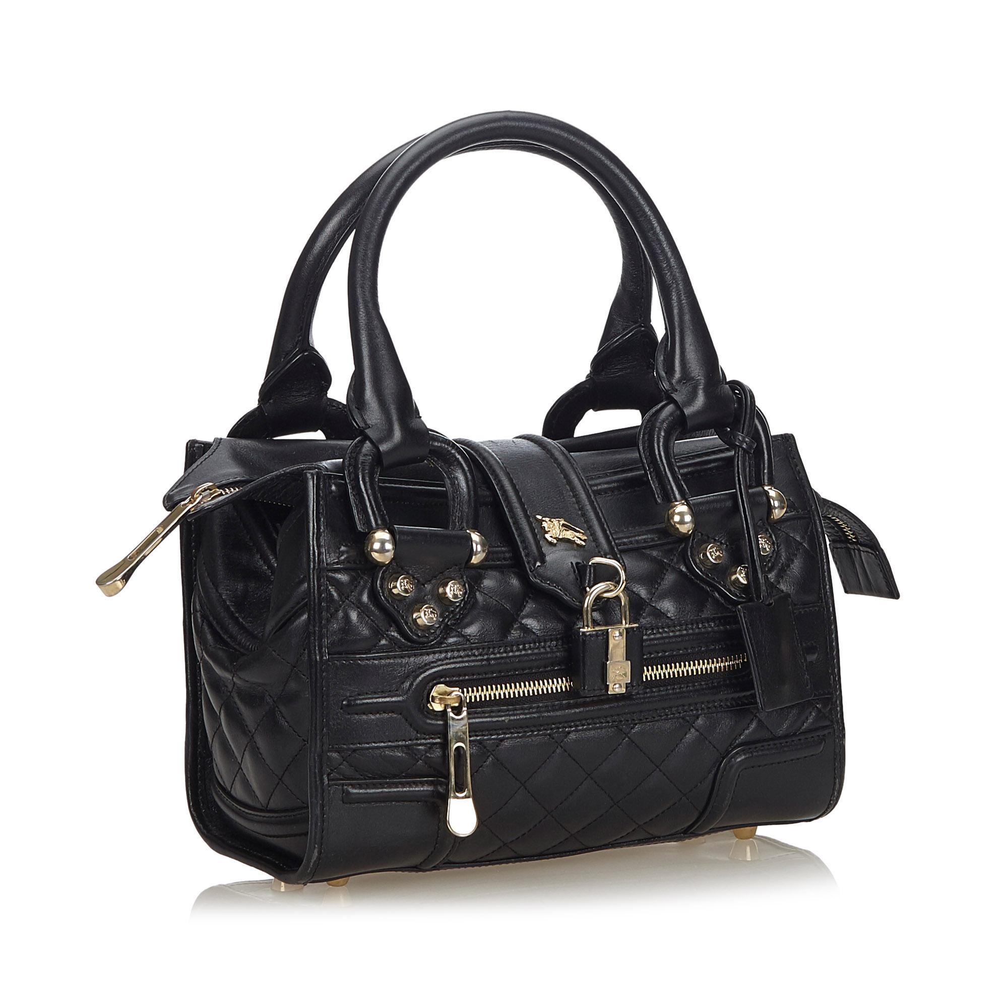 This handbag bag features a quilted leather body, a front exterior zip pocket, rolled leather handles, a front strap with a padlock closure, a top zip closure, and an interior zip pocket. It carries as B+ condition rating.

Inclusions: 
This item