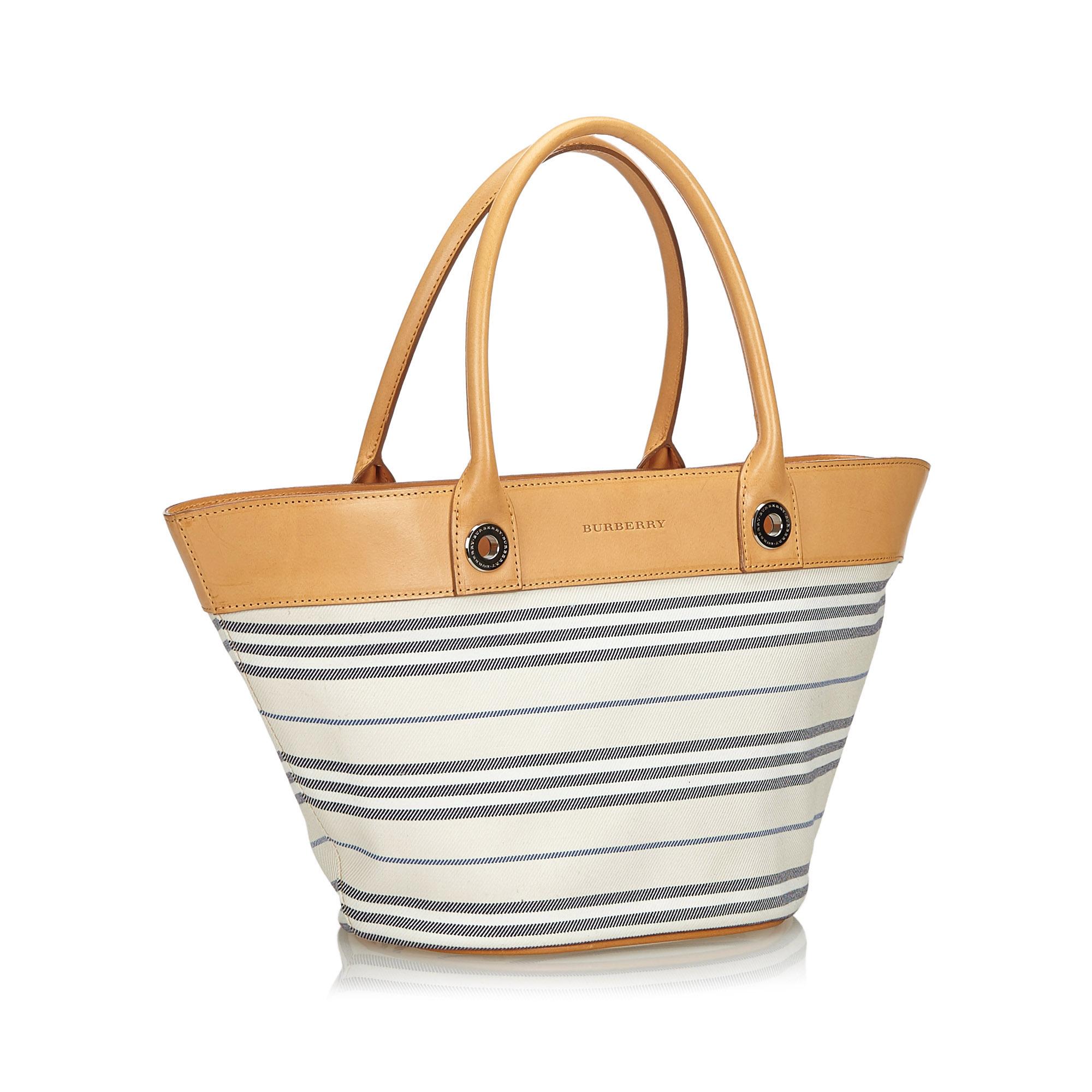 This shoulder bag features a striped canvas body with leather trim, rolled leather handles, an open top, and interior zip and slip pockets. It carries as AB condition rating.

Inclusions: 
This item does not come with