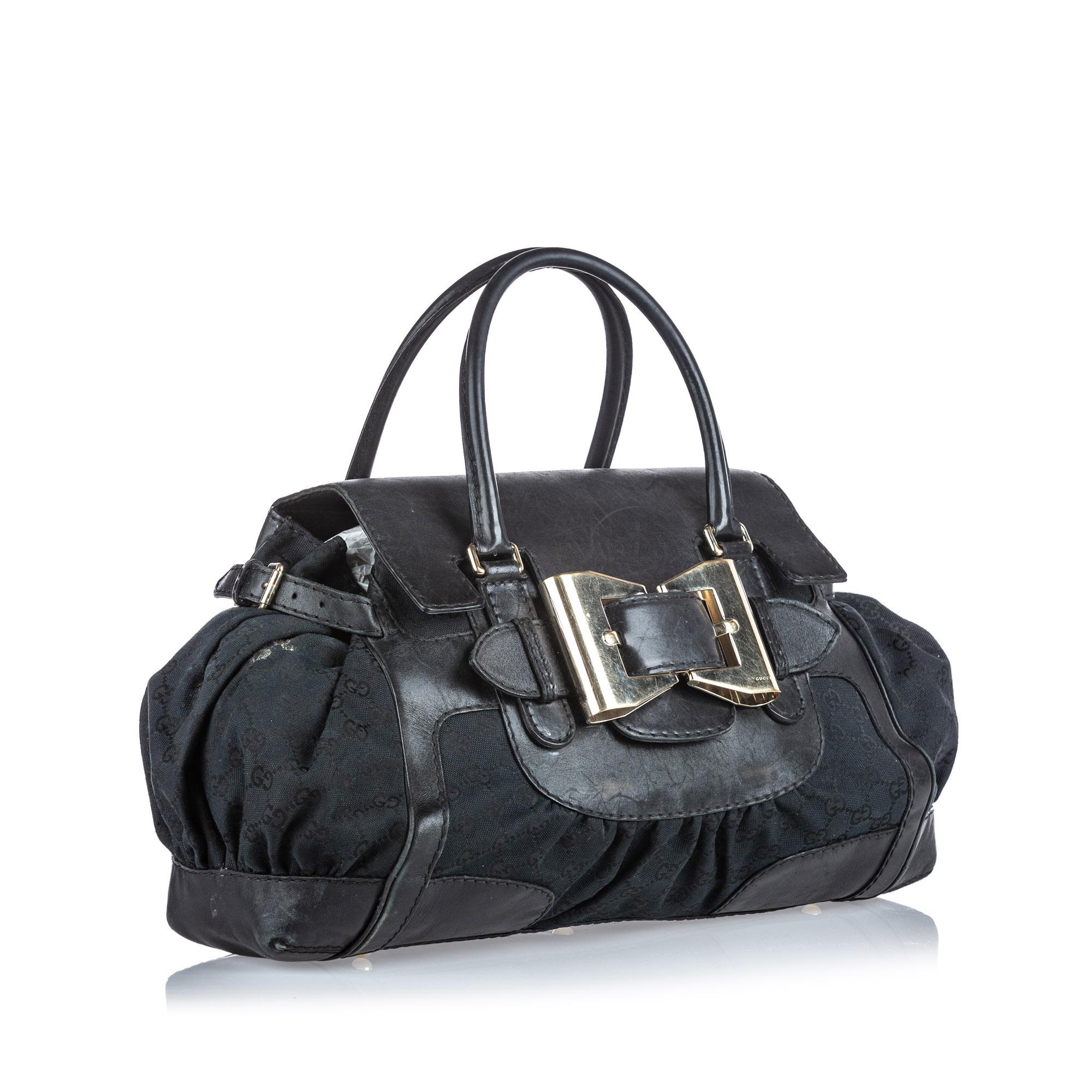 The Dialux Queen handbag features a canvas body with leather trim, an exterior pocket, rolled leather handles, a front flap with buckle details, an open top, and interior zip and slip pockets. It carries as B+ condition rating.

Inclusions: 
This