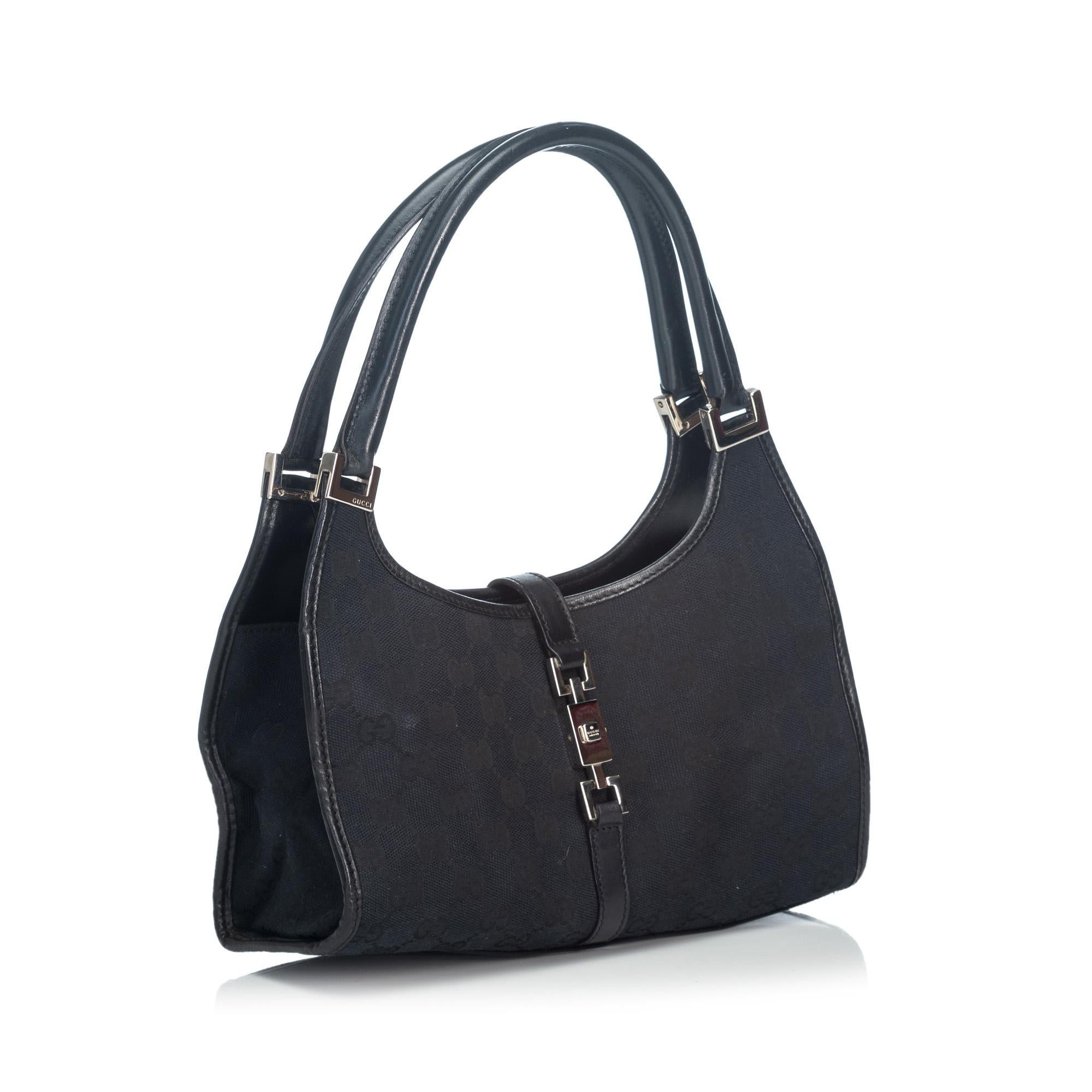 This Jackie features a canvas body with leather trim, rolled leather handles, open top with flat strap and push lock closure, and interior zip pocket. It carries as B+ condition rating.

Inclusions: 
This item does not come with