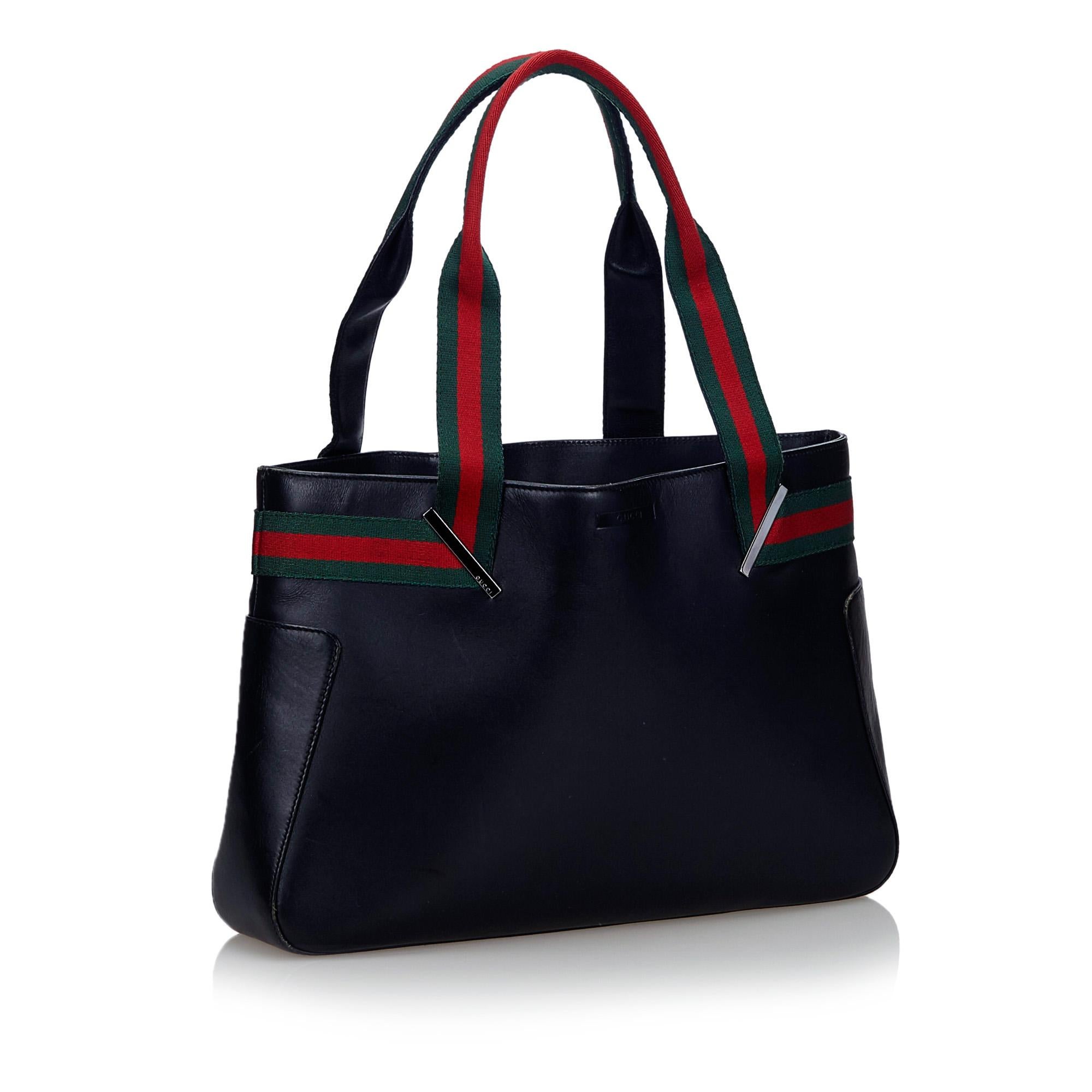 This tote features a leather body, fabric web handles, a top magnetic closure, and an interior zip pocket. It carries as B condition rating.

Inclusions: 
Dust Bag

Dimensions:
Length: 23.00 cm
Width: 36.00 cm
Depth: 7.00 cm
Shoulder Drop: 19.00