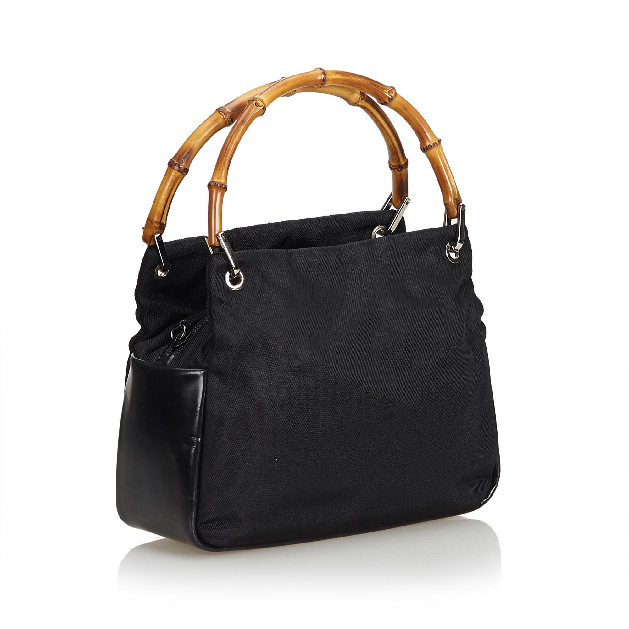 This handbag features a nylon body with leather trim, exterior side compartments, bamboo handles, a top zip closure, and an interior zip pocket. It carries as B+ condition rating.

Inclusions: 
This item does not come with
