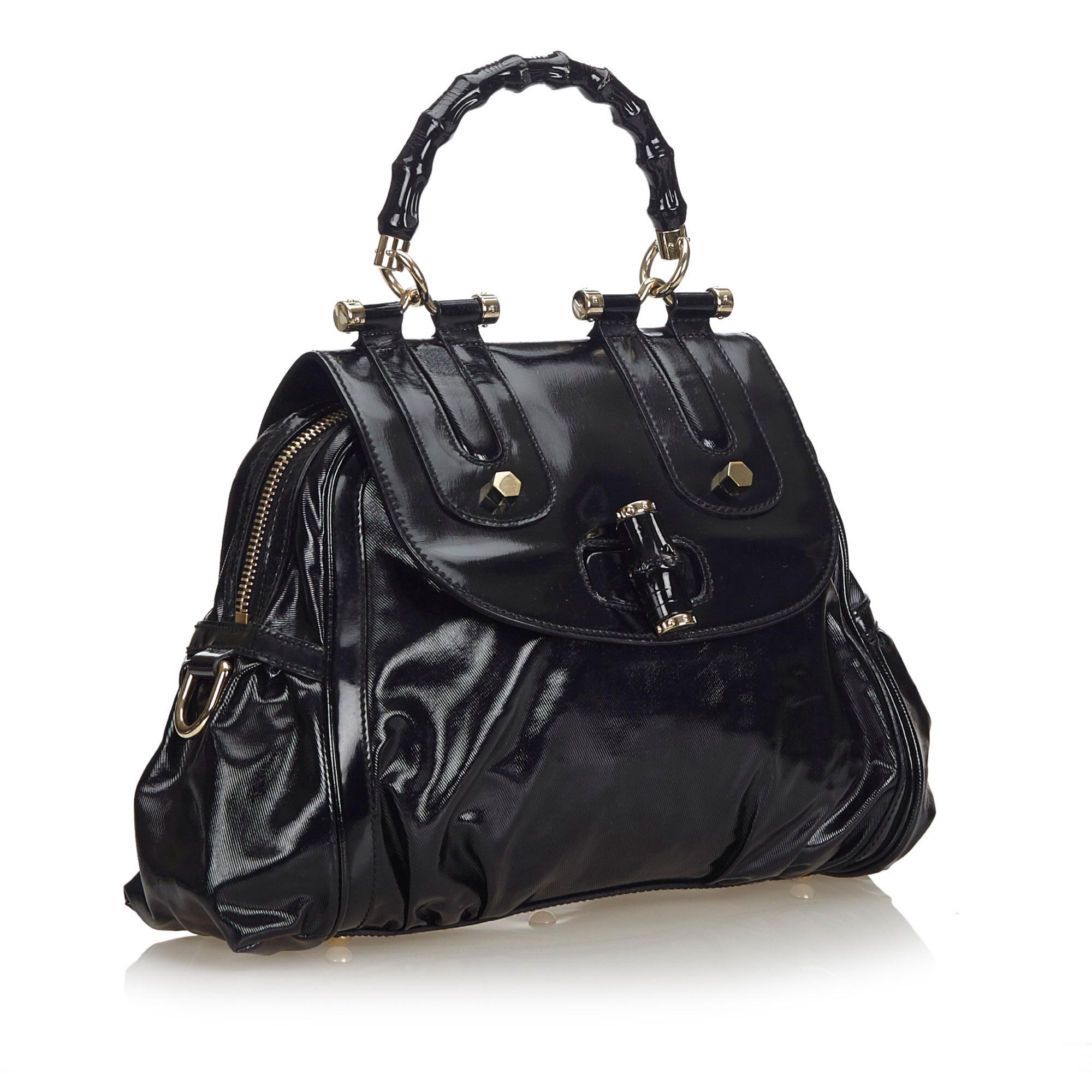 This satchel features a patent leather body, a bamboo top handle, a detachable flat leather strap, a front flap with a bamboo twist lock closure, a top zip closure, and interior zip and slip pockets. It carries as AB condition rating.

Inclusions: