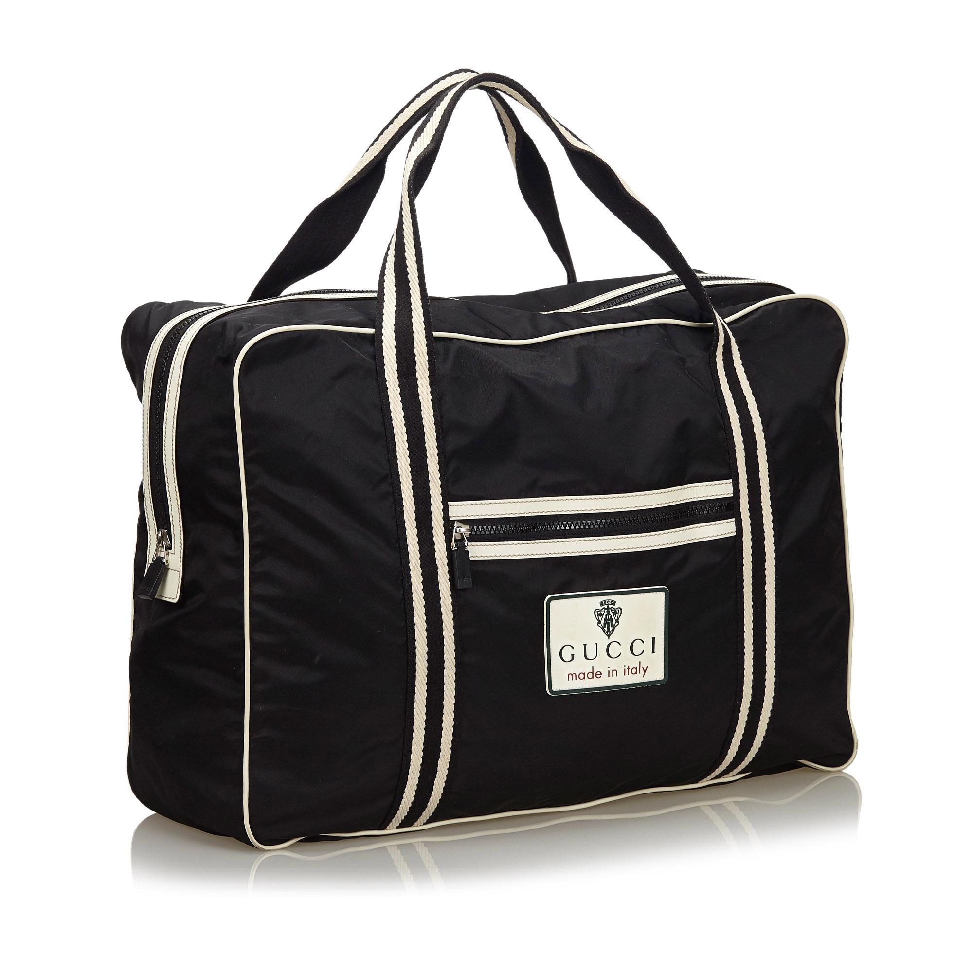 This travel bag features a nylon body with leather trim, a front exterior zip pocket, flat handles, a top zip closure, and interior slip pockets. It carries as B+ condition rating.

Inclusions: 
This item does not come with