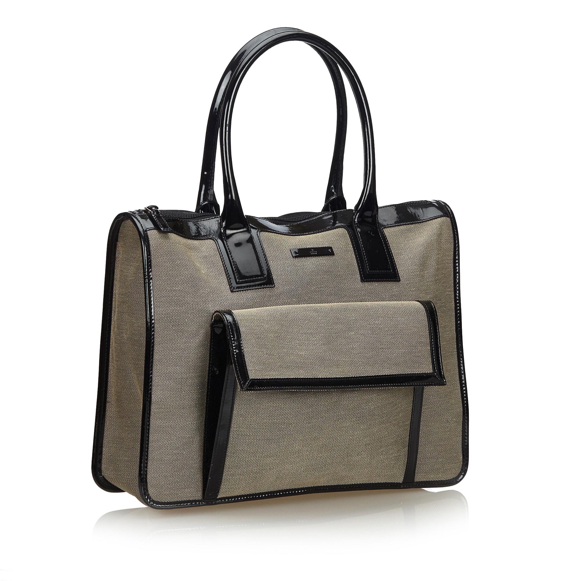 This handbag features a canvas body with patent leather trim, a front exterior flap pocket, rolled leather handles, a top zip closure, and an interior zip pocket. It carries as B+ condition rating.

Inclusions: 
This item does not come with