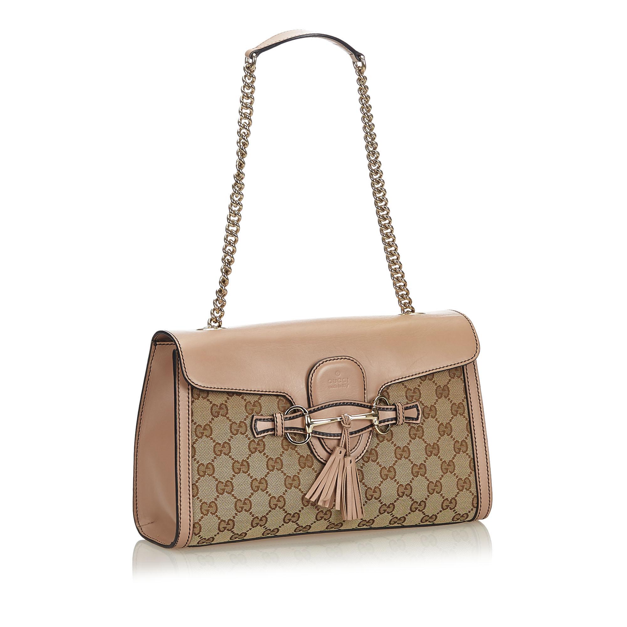 The Emily features a canvas body with leather trim, a gold-tone curb chain strap, a front flap with a tuck closure and a tassel detail, and interior slip pockets. It carries as B+ condition rating.

Inclusions: 
Dust Bag
Dimensions:
Length: 20.00