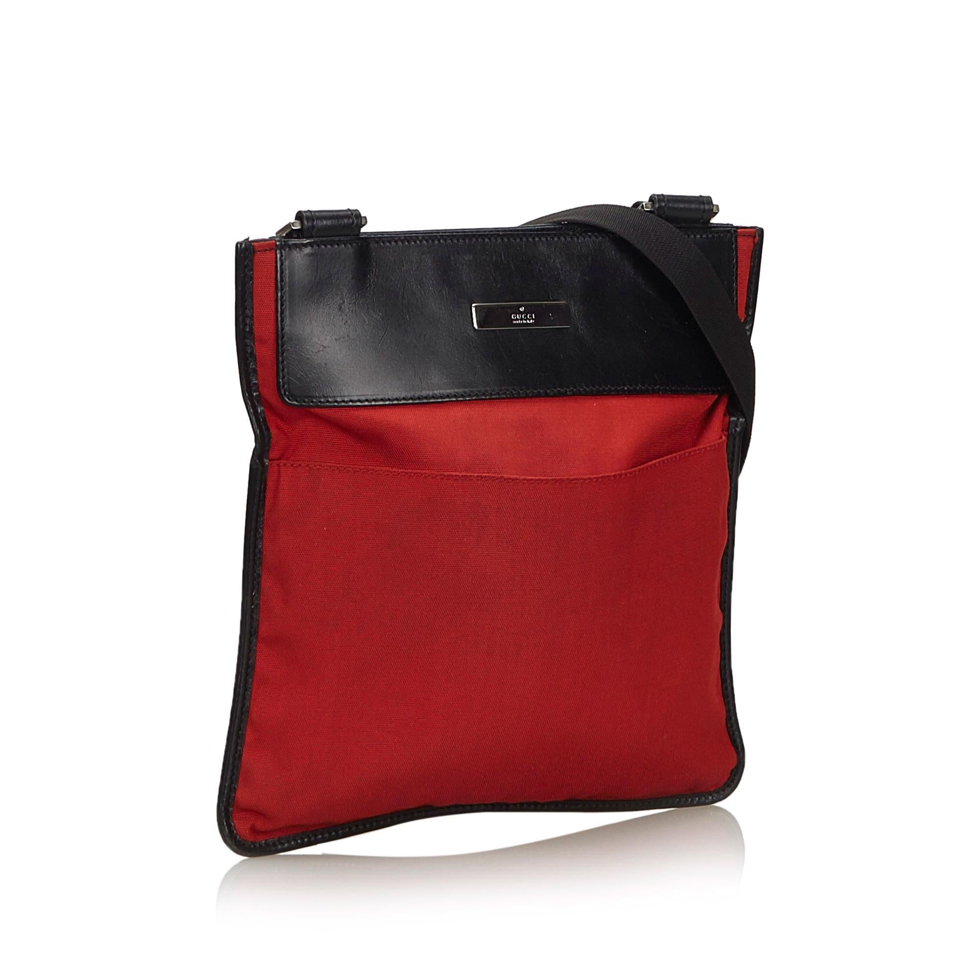 This crossbody bag features a nylon body with leather trim, front and back exterior slip pockets, a flat strap, an open top, and an interior zip pocket. It carries as B+ condition rating.

Inclusions: 
This item does not come with