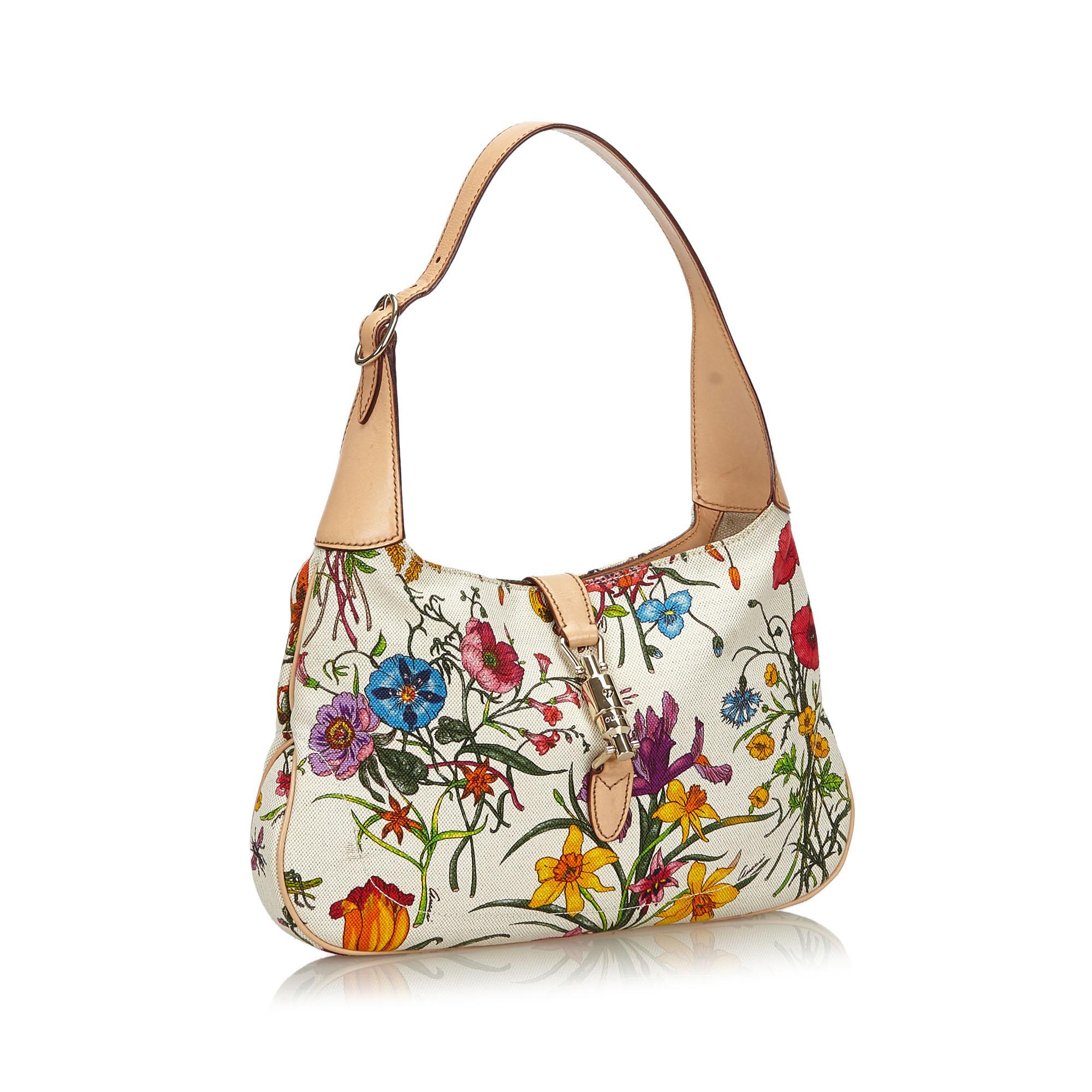The Jackie shoulder bag features a floral canvas body, a flat shoulder strap, a front strap with a push lock closure, and an interior zip pocket. It carries as B+ condition rating.

Inclusions: 
This item does not come with