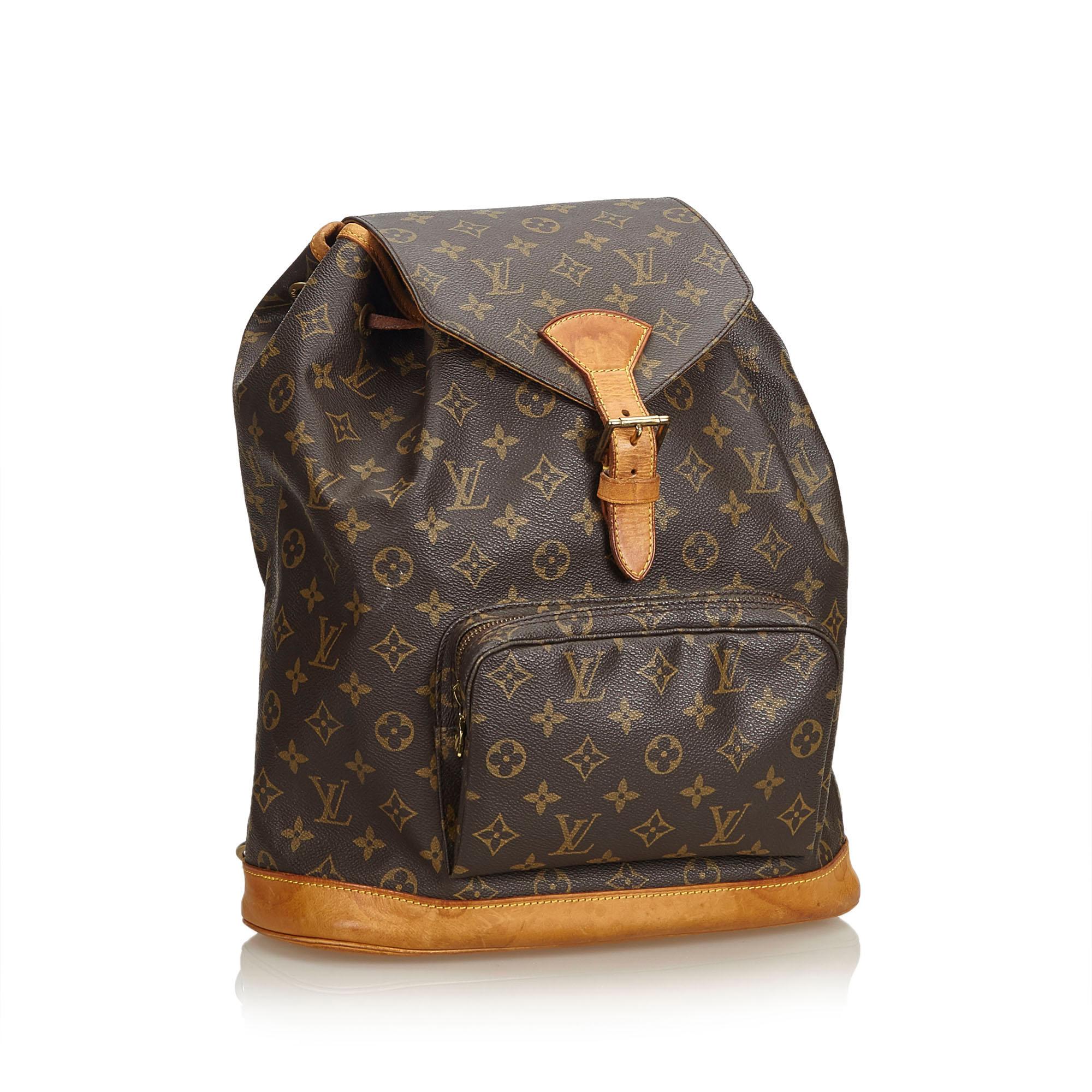 The Montsouris GM features a monogram canvas body, flat shoulder straps, a leather bottom, a front flap with a belt buckle detail and a magnetic closure, a top drawstring closure, and an interior slip pocket. It carries as B condition